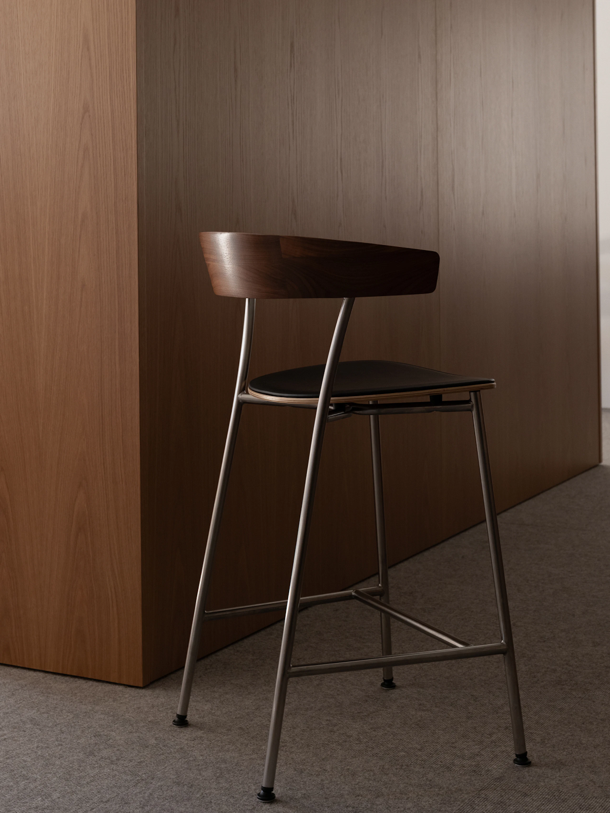 A Leeway Stool in natural walnut with a black leather seat
