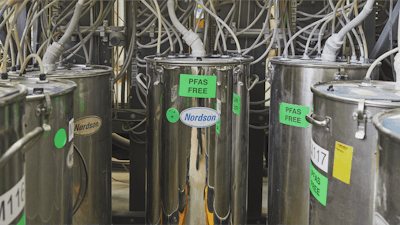 Several large, silver Nordson brand chemical tanks with green stickers that read PFAS FREE.