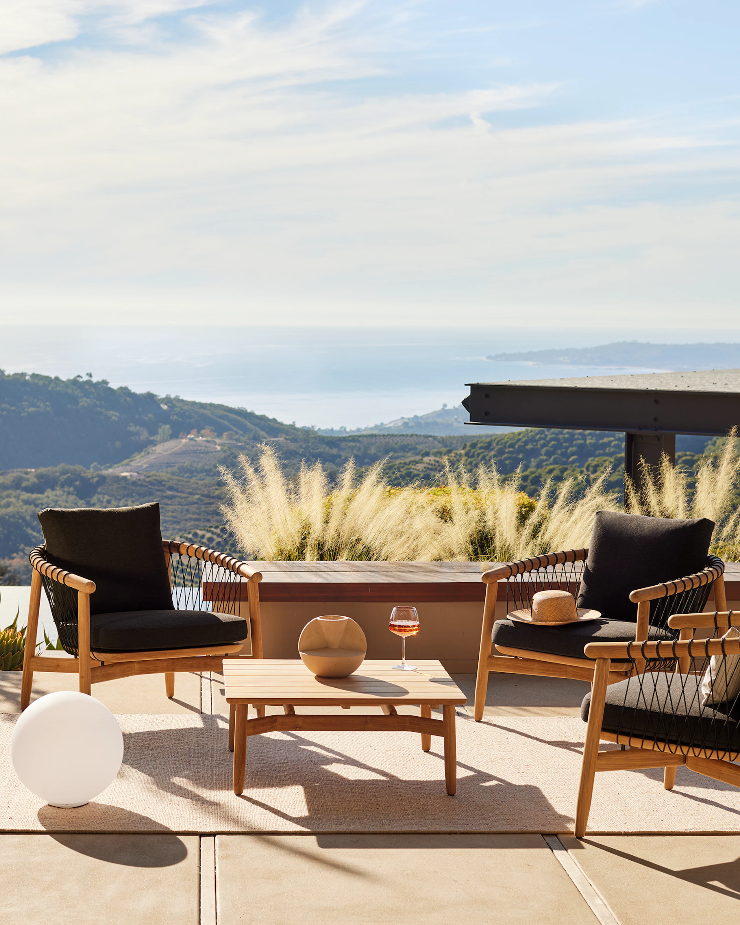 Crosshatch Outdoor Lounge Chairs and Square Coffee Table in an environmental setting overlooking mountain and ocean views.