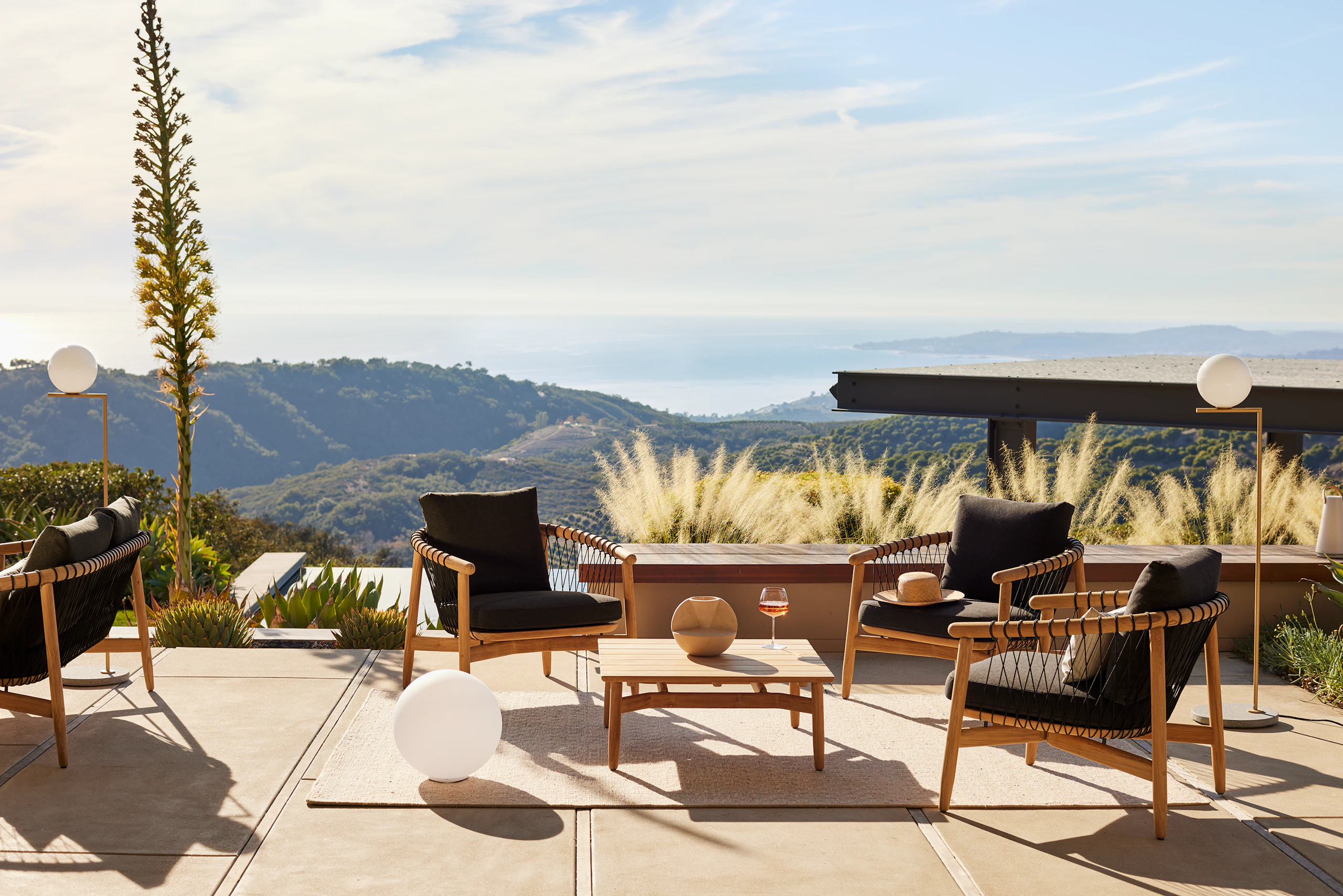 Crosshatch Outdoor Lounge Chairs and Square Coffee Table in an environmental setting overlooking mountain and ocean views.