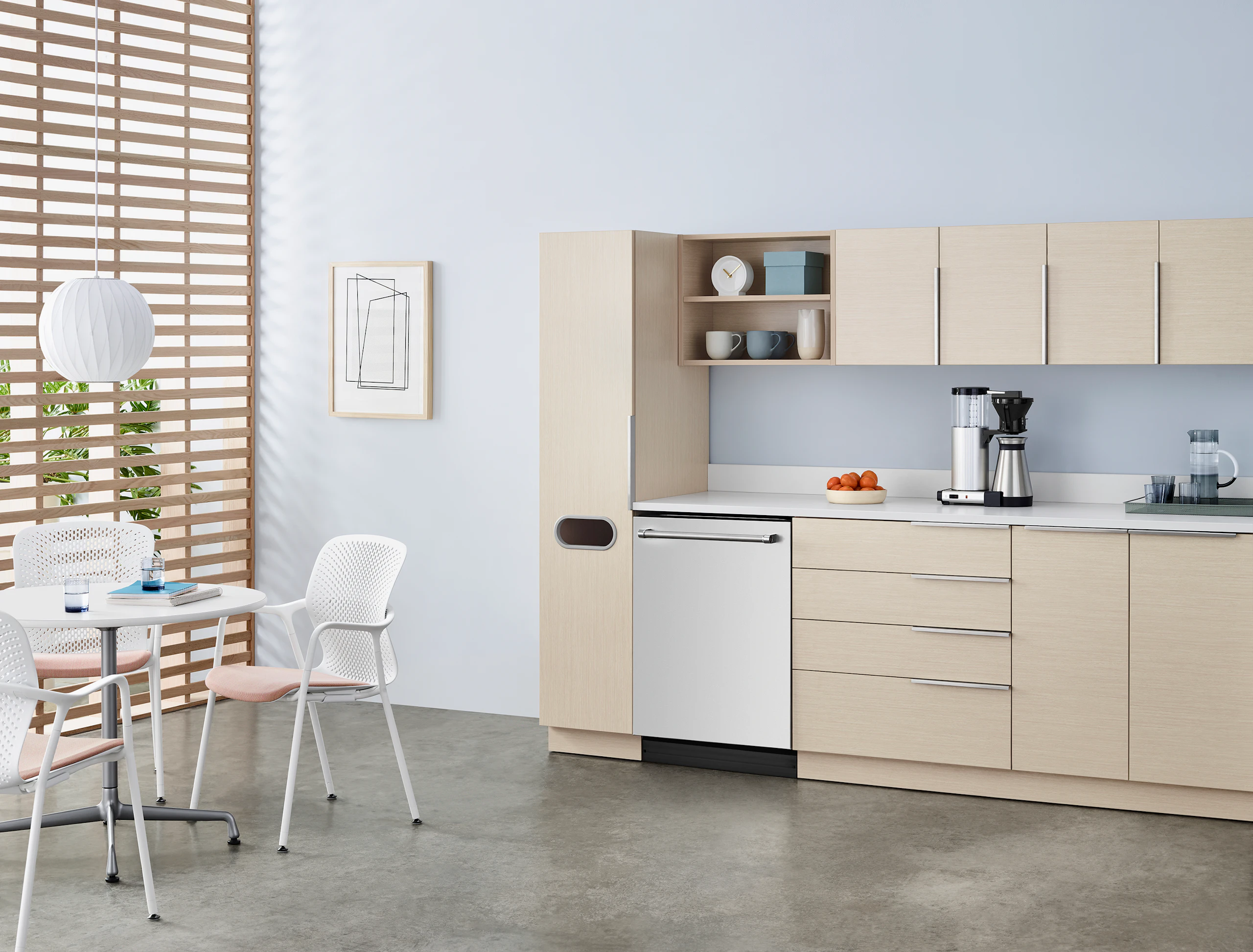 A staff lounge setting with Mora System casework in an ash finish with a storage tower, upper and lower storage, and a white sink and integrated backsplash.