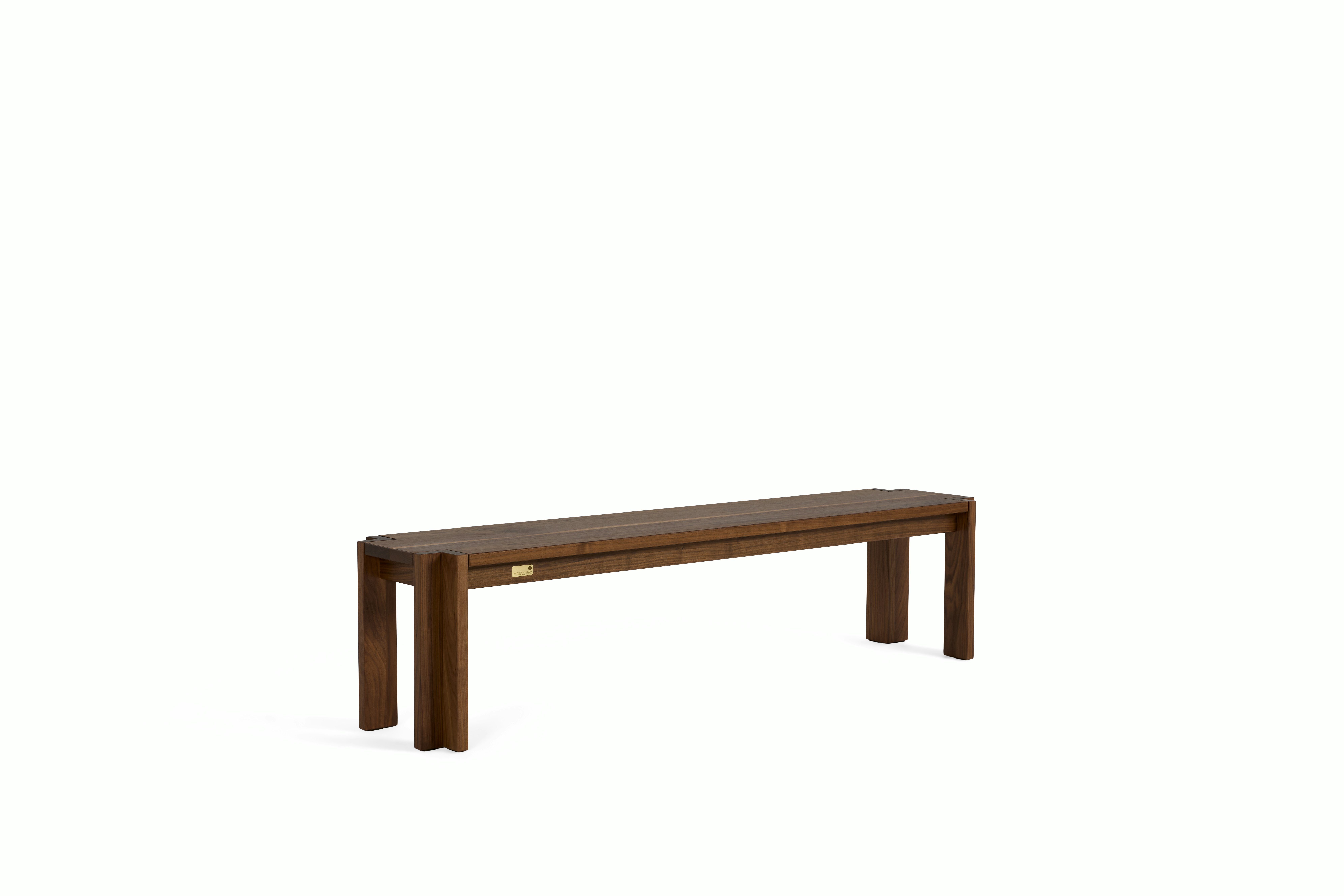 A Utzon Dining Bench in Walnut viewed from an angle.