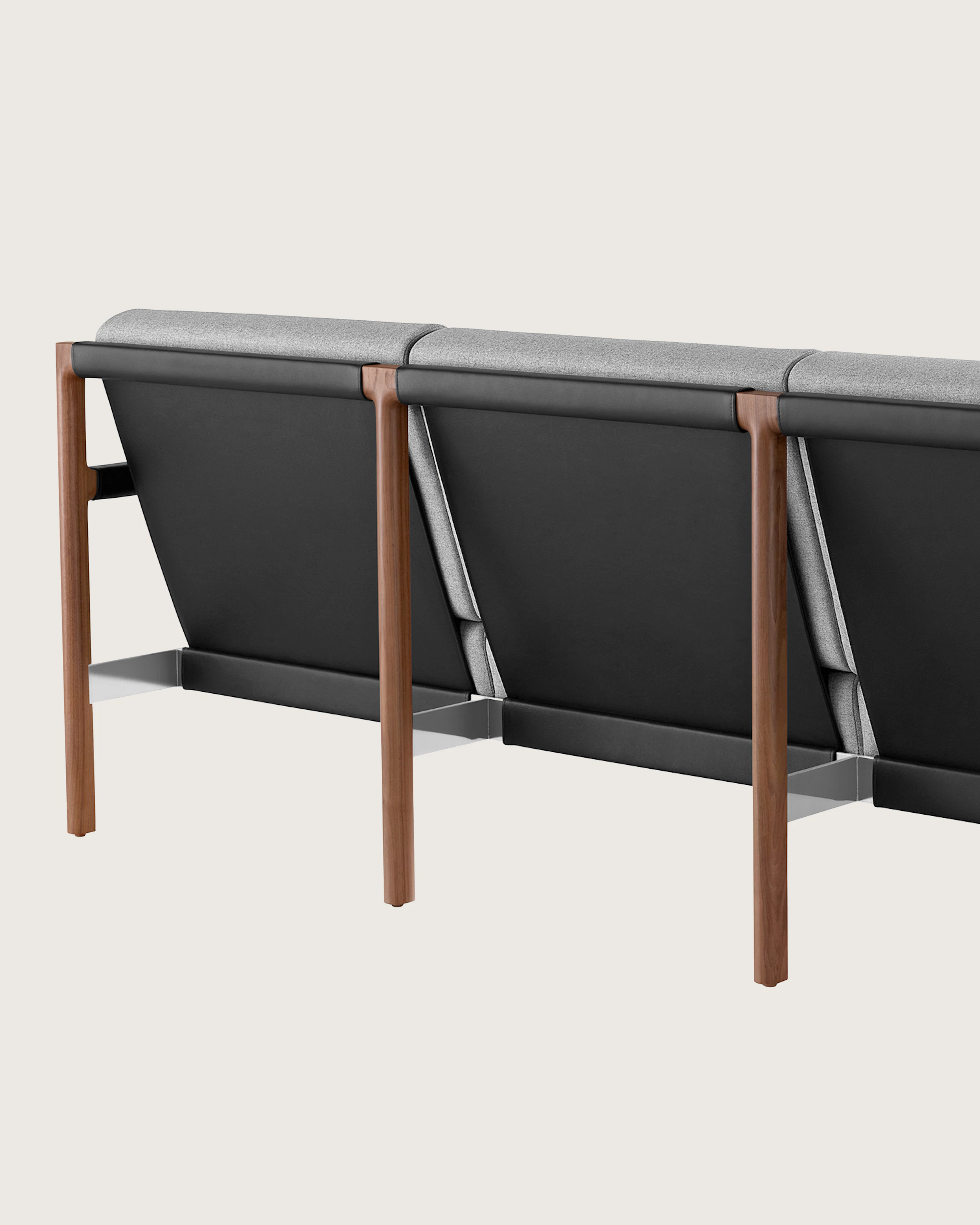 A Brabo Sofa with light gray upholstery, leather and metal accents, and an exposed wood frame. Viewed from the back at an angle.