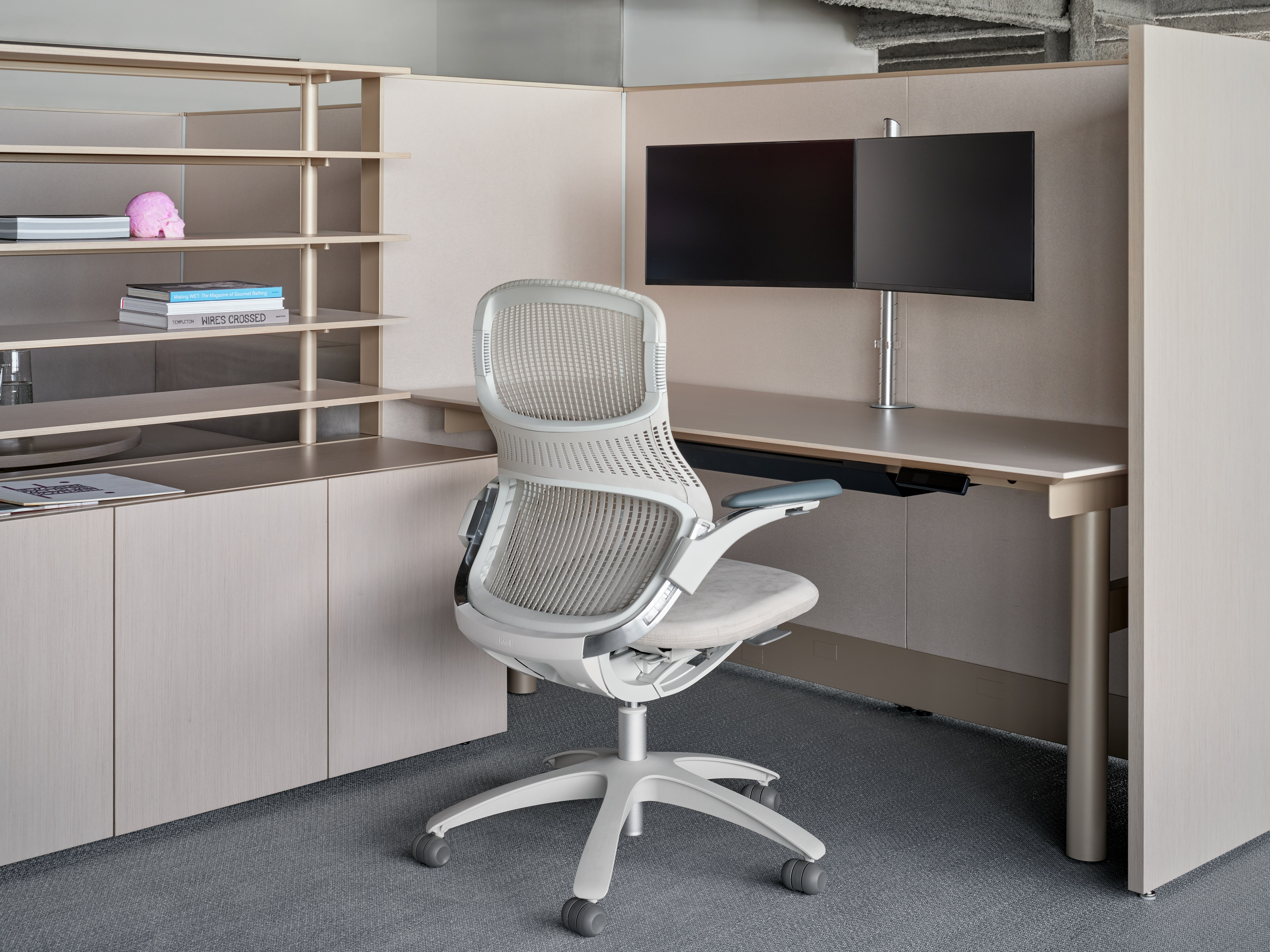 A skyline table and panel system is viewed from an angle with open shelving next to the desk. The shelves are on top of storage credenza with a work chair in front of the desk.