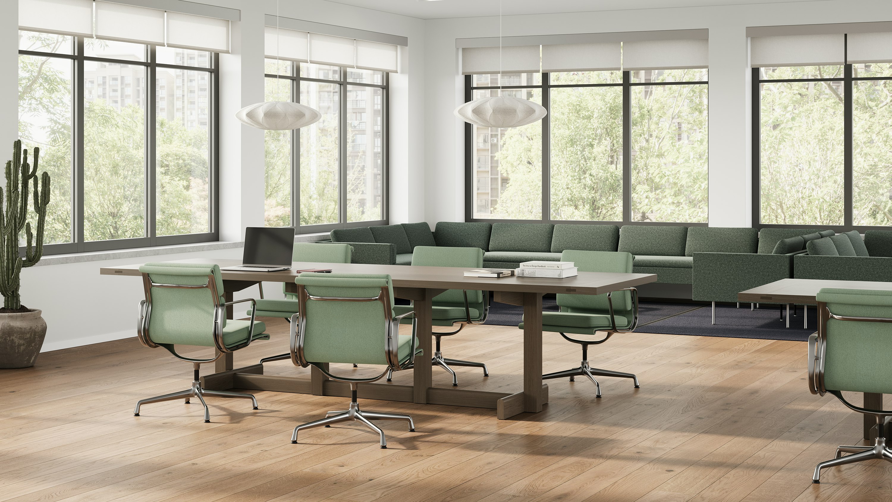 Long wooden Land Table with office chairs surrounding and green Lispenard Sofa in back