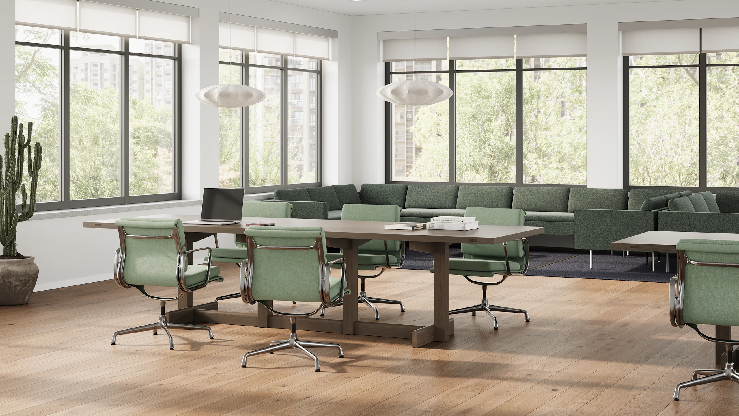 Long wooden Land Table with office chairs surrounding and green Lispenard Sofa in back