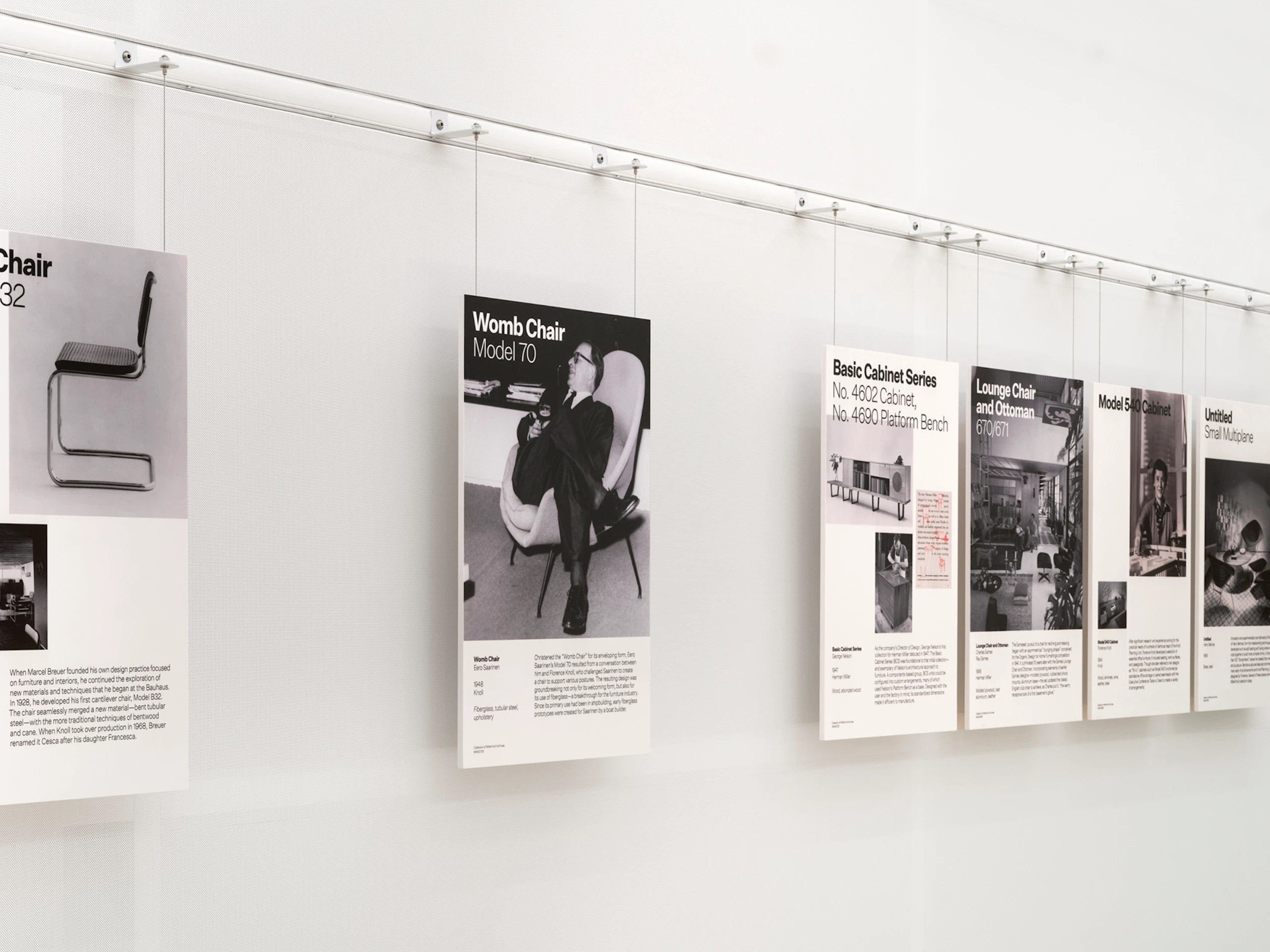 Informational placards for the Cesca Chair, Womb Chair, Eames Lounge Chair and Ottoman, and more on a wall display at the MillerKnoll Archives