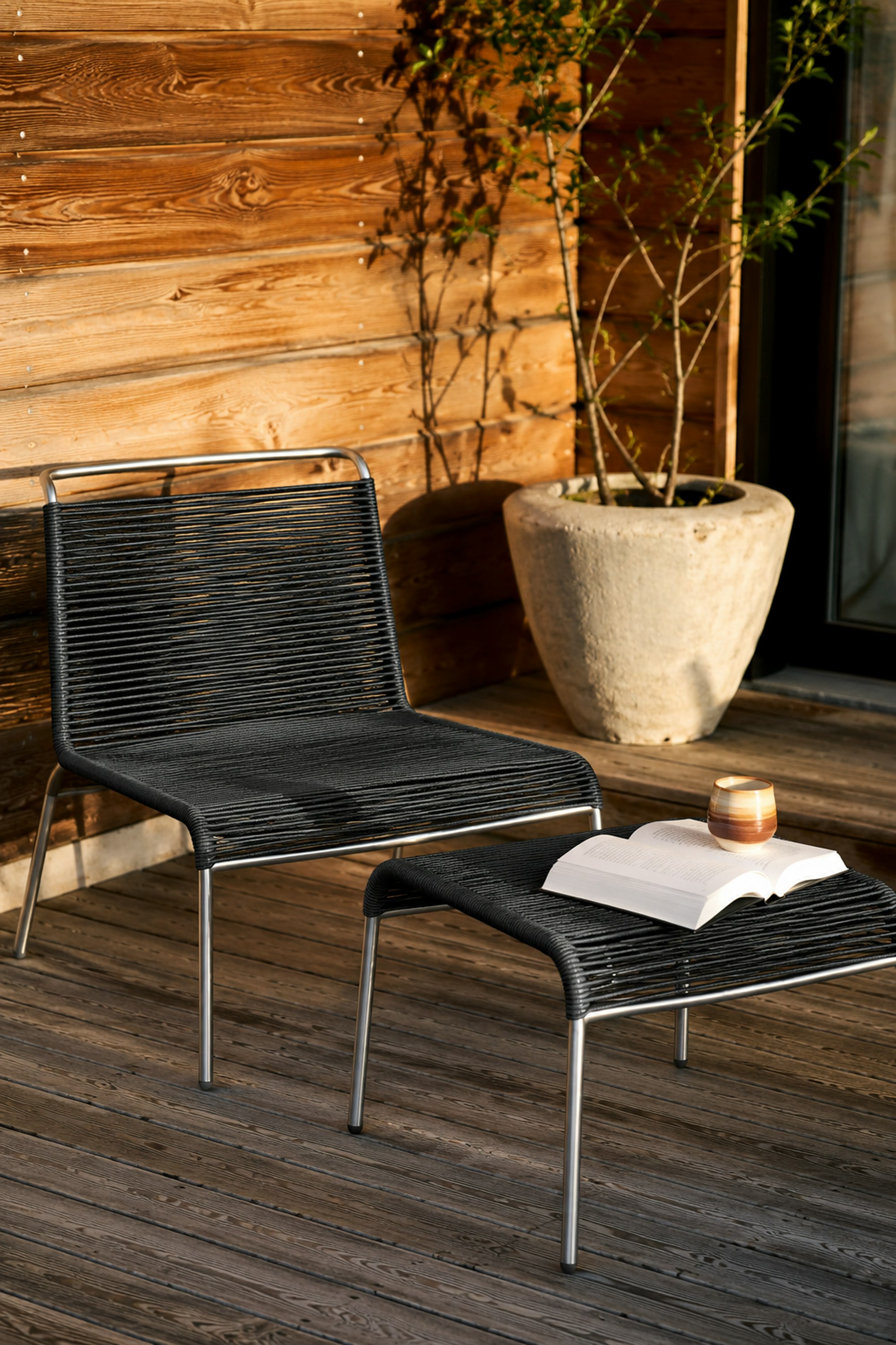 An environmental shot of Teglgaard Outdoor Ottoman in Black.