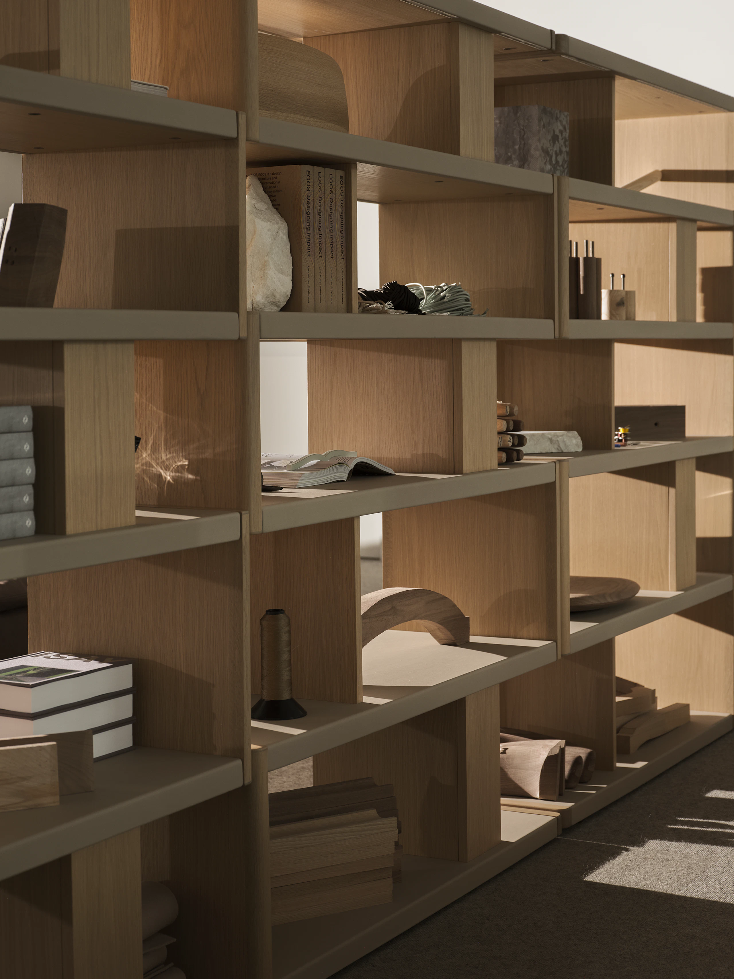 Various New Canaan Tall Bookshelves in Light Oak wrapped with Bristol Leather in Champagne arranged side by side and styled with various objects, viewed at an angle.