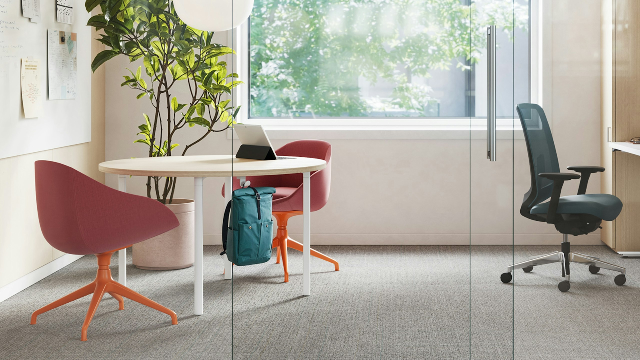 Seating area in a private faculty office furnished with two red-orange NaughtOne Always chairs, a Herman Miller Everywhere table, and Herman Miller Verus chair.