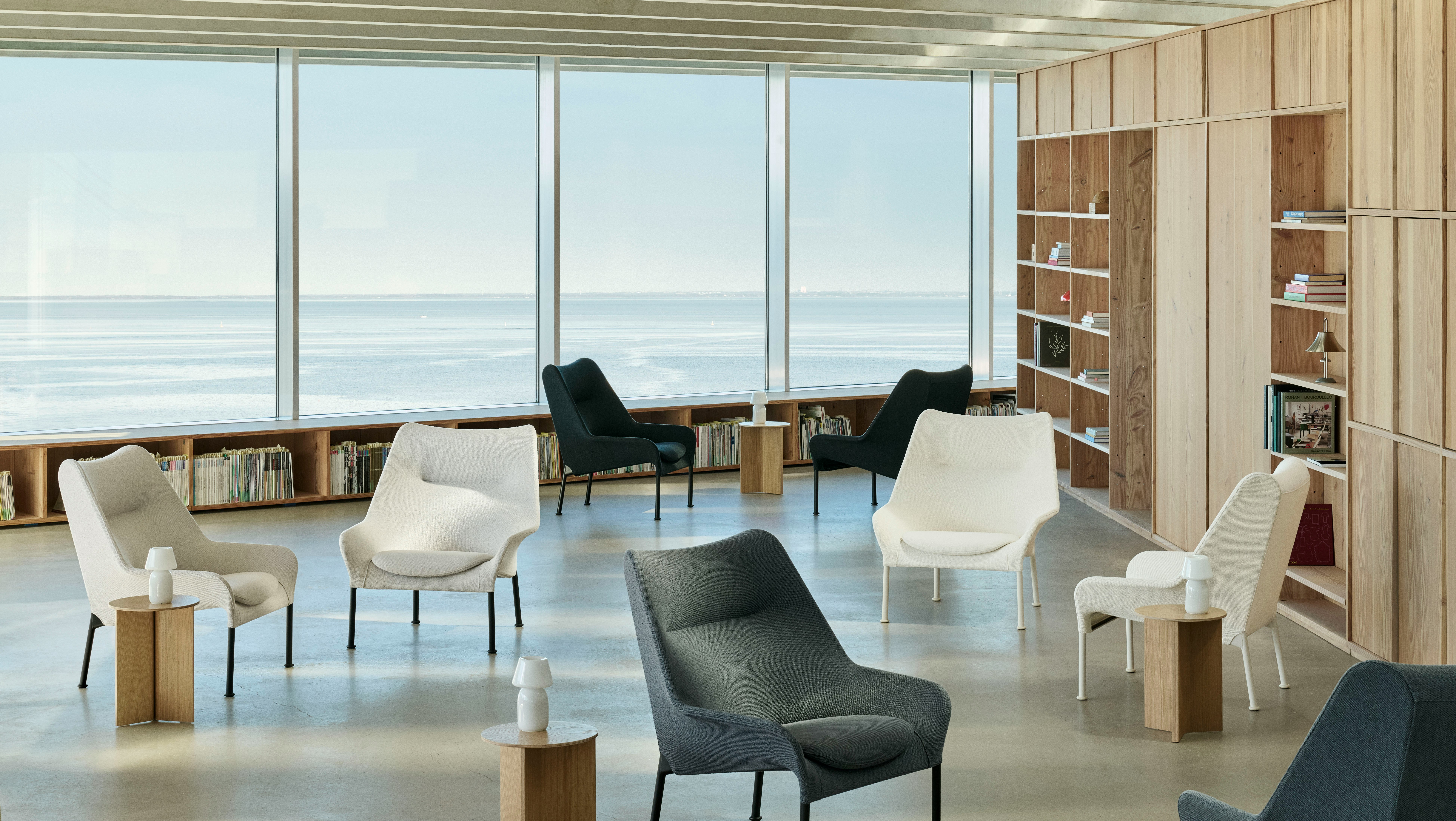 Lifestyle shot of multiple O2 lounge chairs and Wood Slit Tables in a glass-walled workspace.