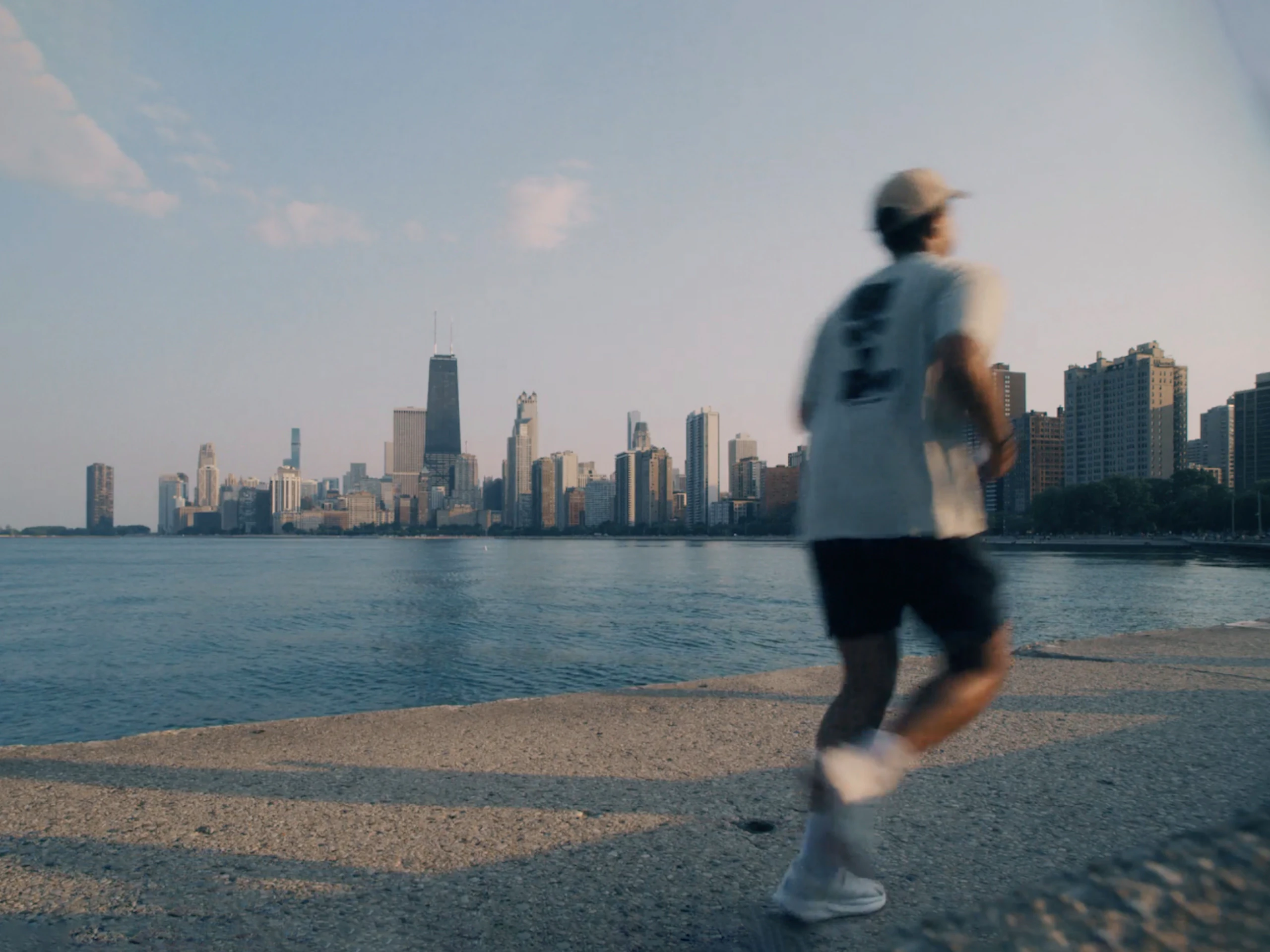 A person jogging along the water with the Chicago Skyline in the background