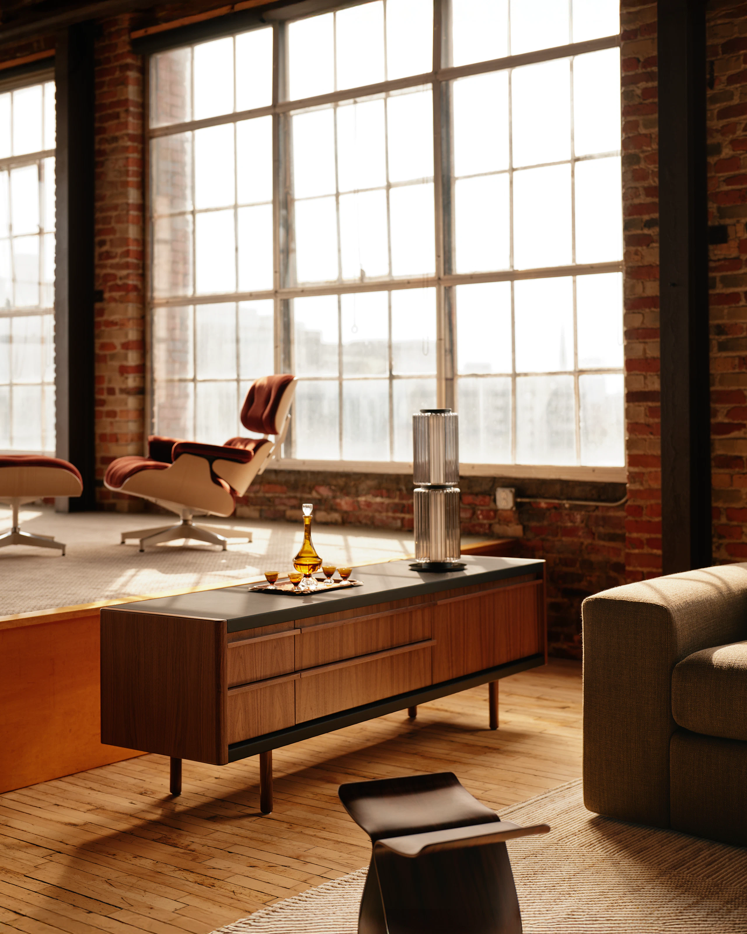 New Canaan Media Unit designed by BassamFellows for Geiger in Walnut with Black Leather shown angled in a residential setting.