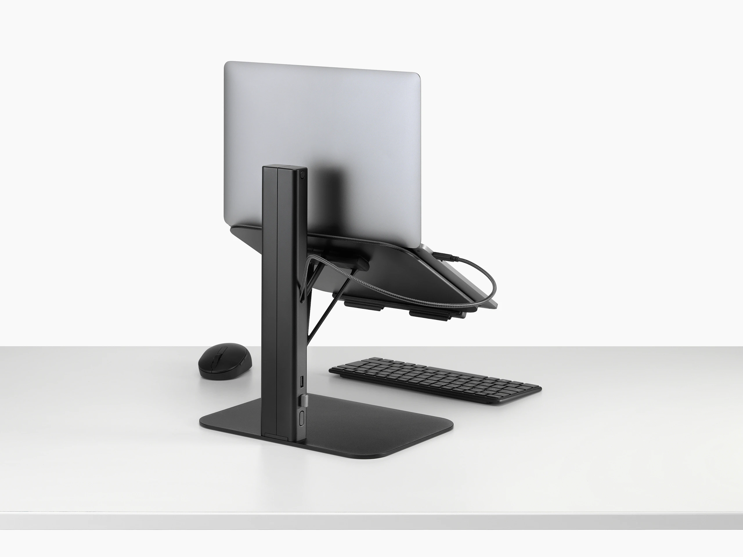 Lana laptop stand with laptop keyboard and mouse in black viewed from a back sided angle.