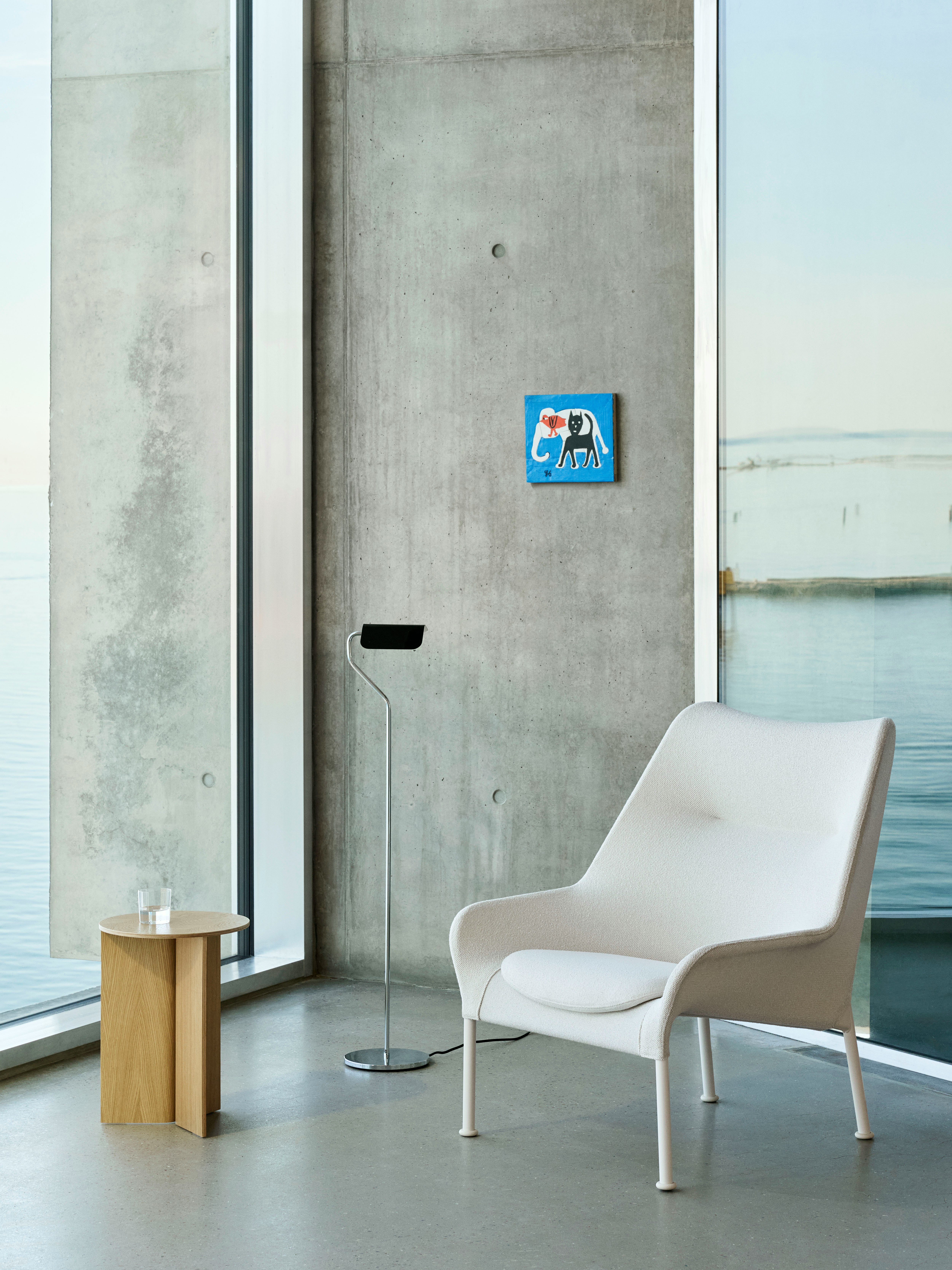 O2 Lounge Chair and Wood Slit Table staged in a concrete and glass lobby with artwork on the wall.