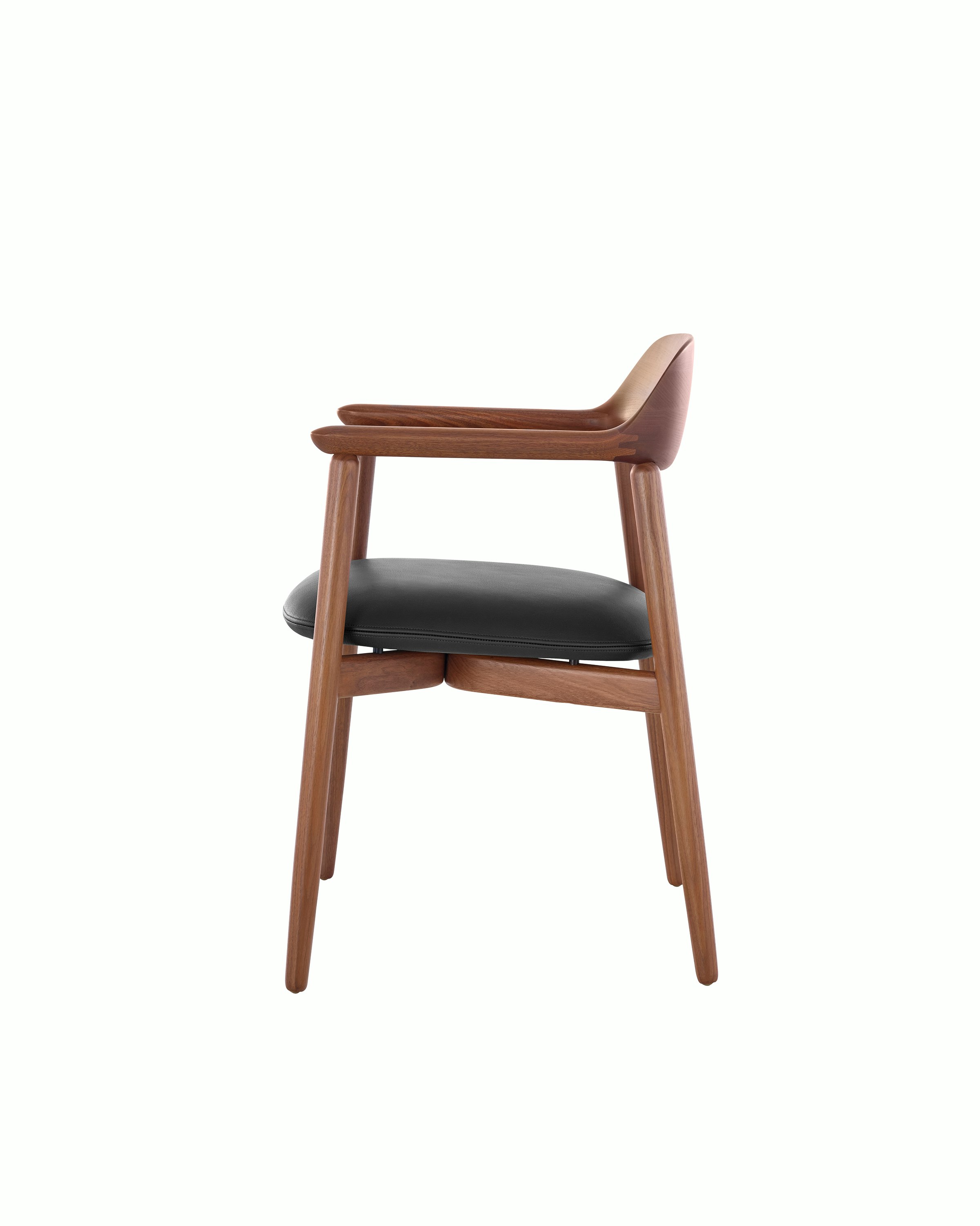 Side view of a Crosshatch Side Chair with a medium wood finish and black leather seat pad, showing the meticulous craftsmanship.