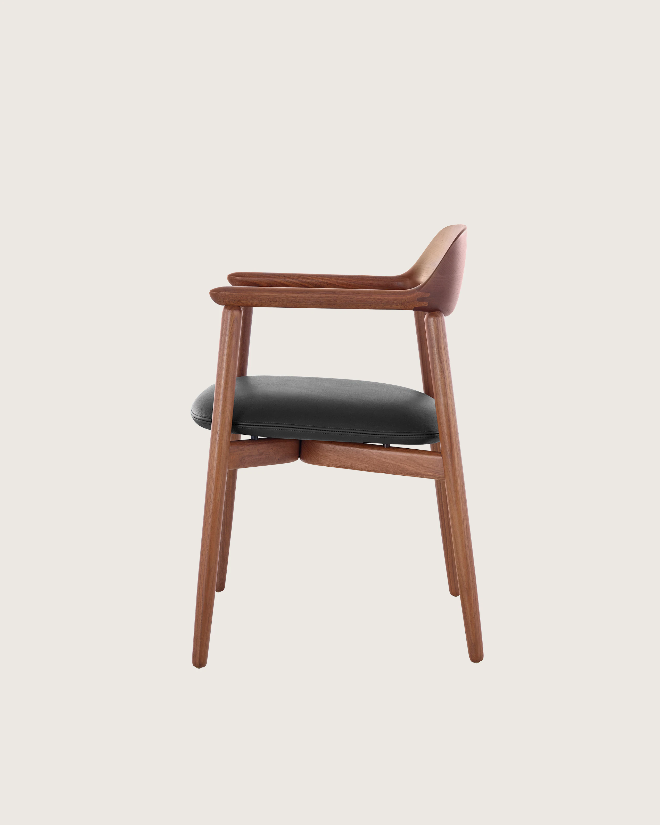 Side view of a Crosshatch Side Chair with a medium wood finish and black leather seat pad, showing the meticulous craftsmanship.