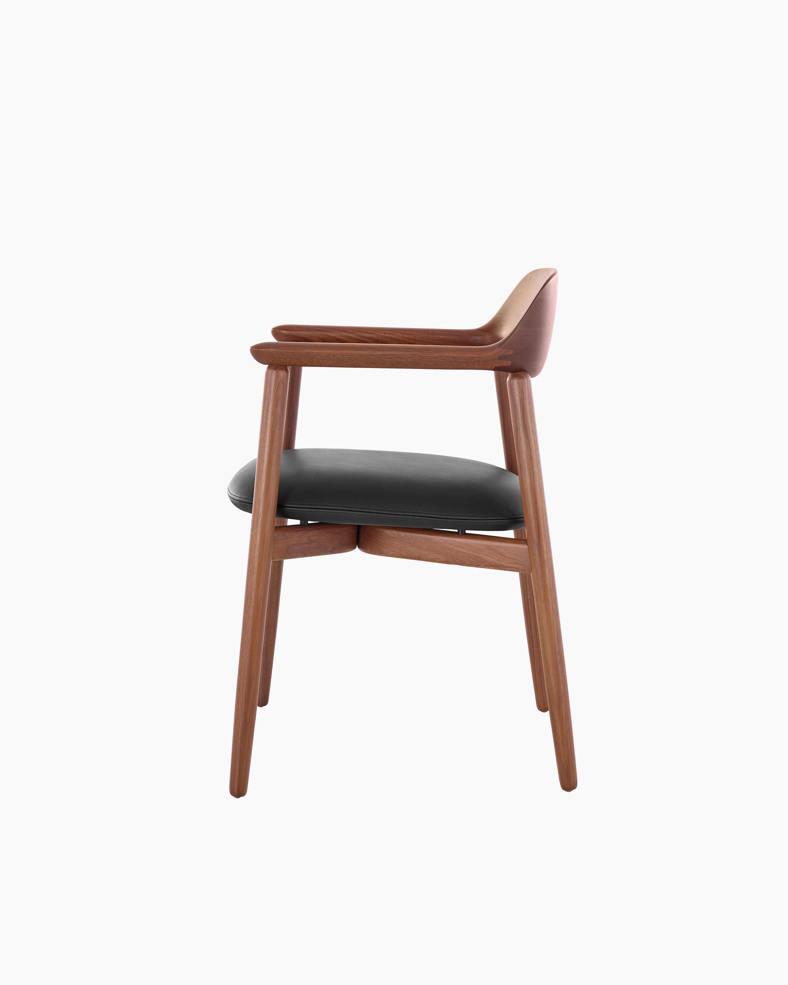 Side view of a Crosshatch Side Chair with a medium wood finish and black leather seat pad, showing the meticulous craftsmanship.
