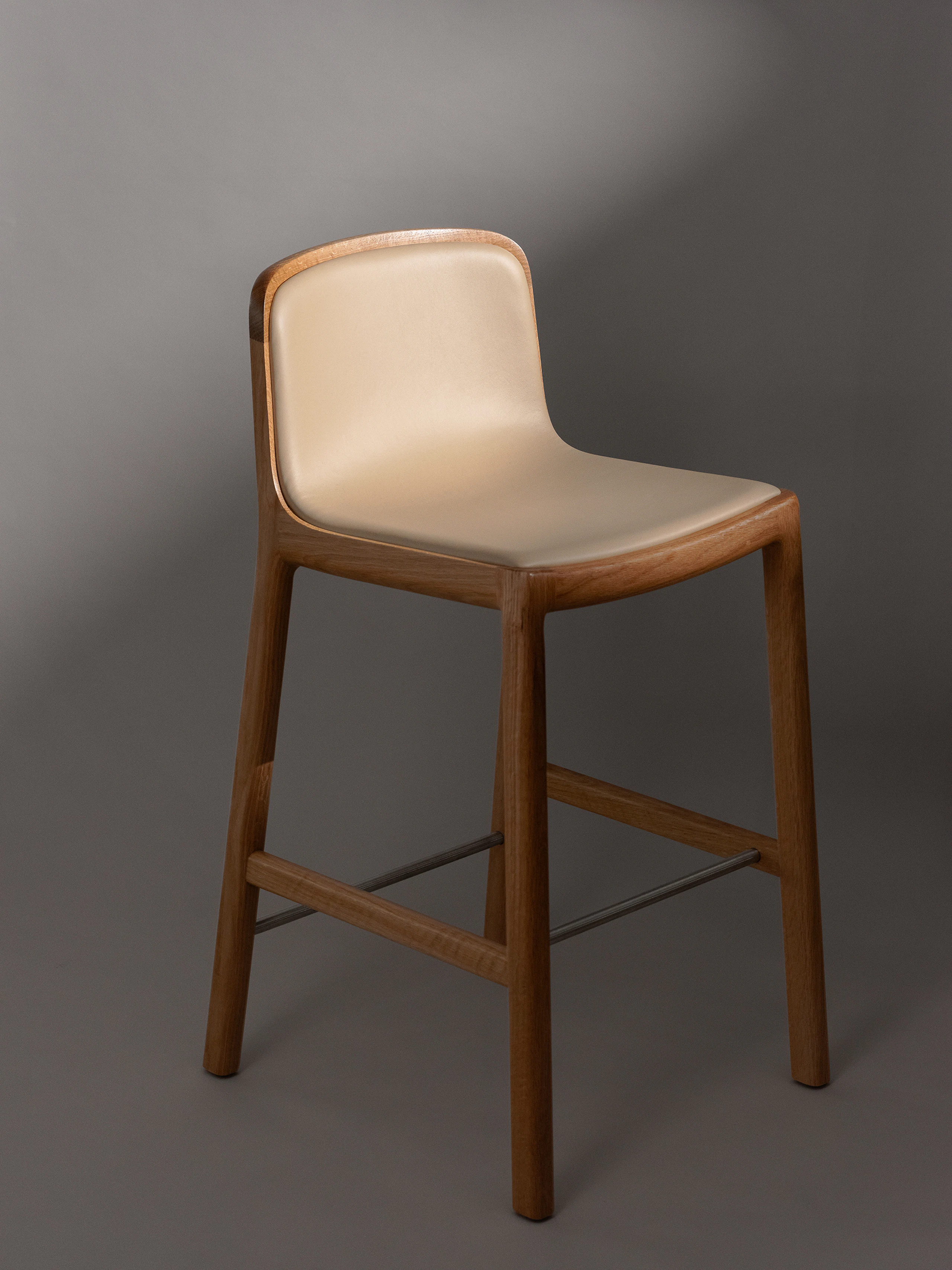 A counter height Lijn Stool in Natural Oak fully upholstered with Bristol leather in Champagne, viewed at an angle.