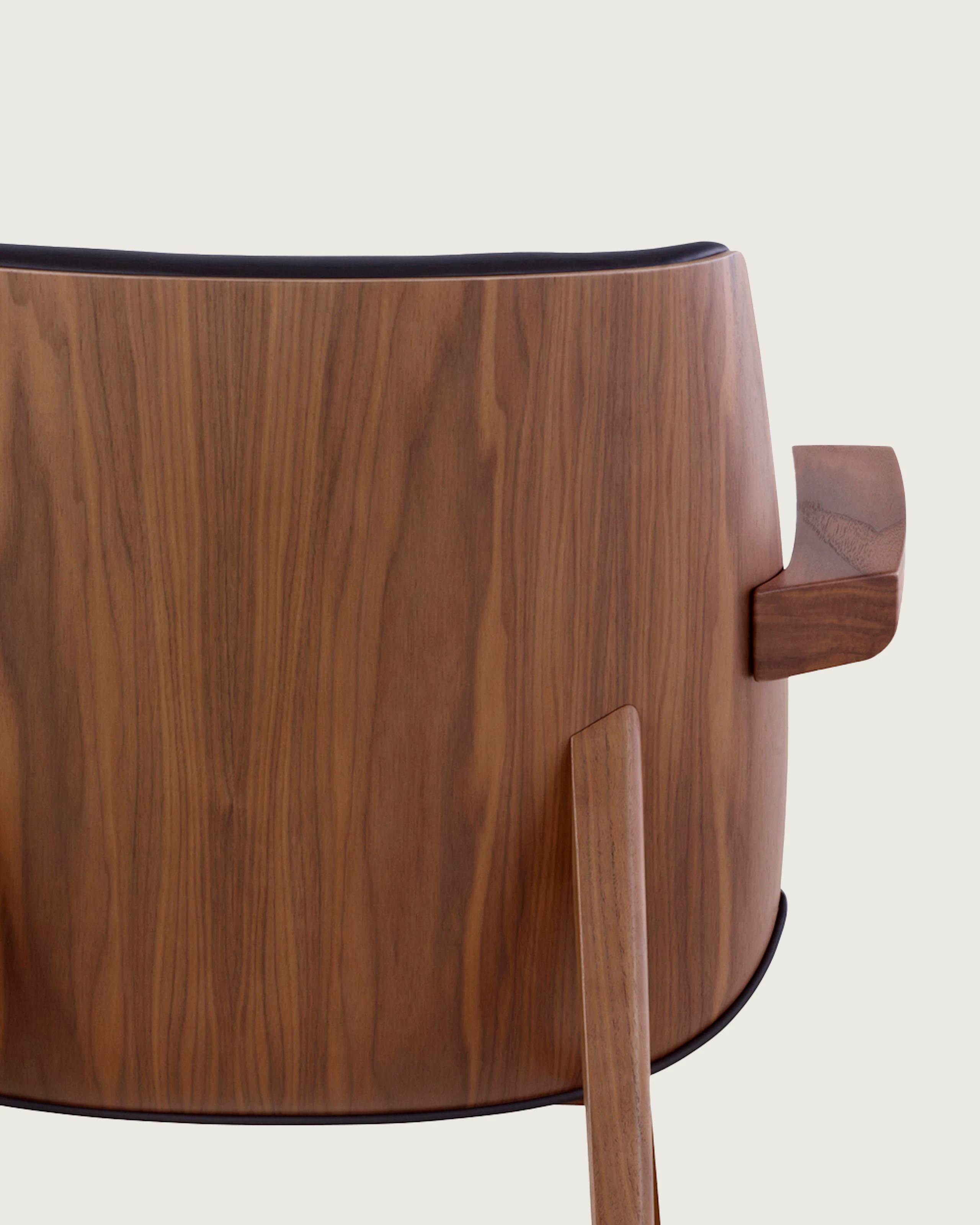 Back view of a low-back Clamshell Lounge Chair with black leather and walnut legs.