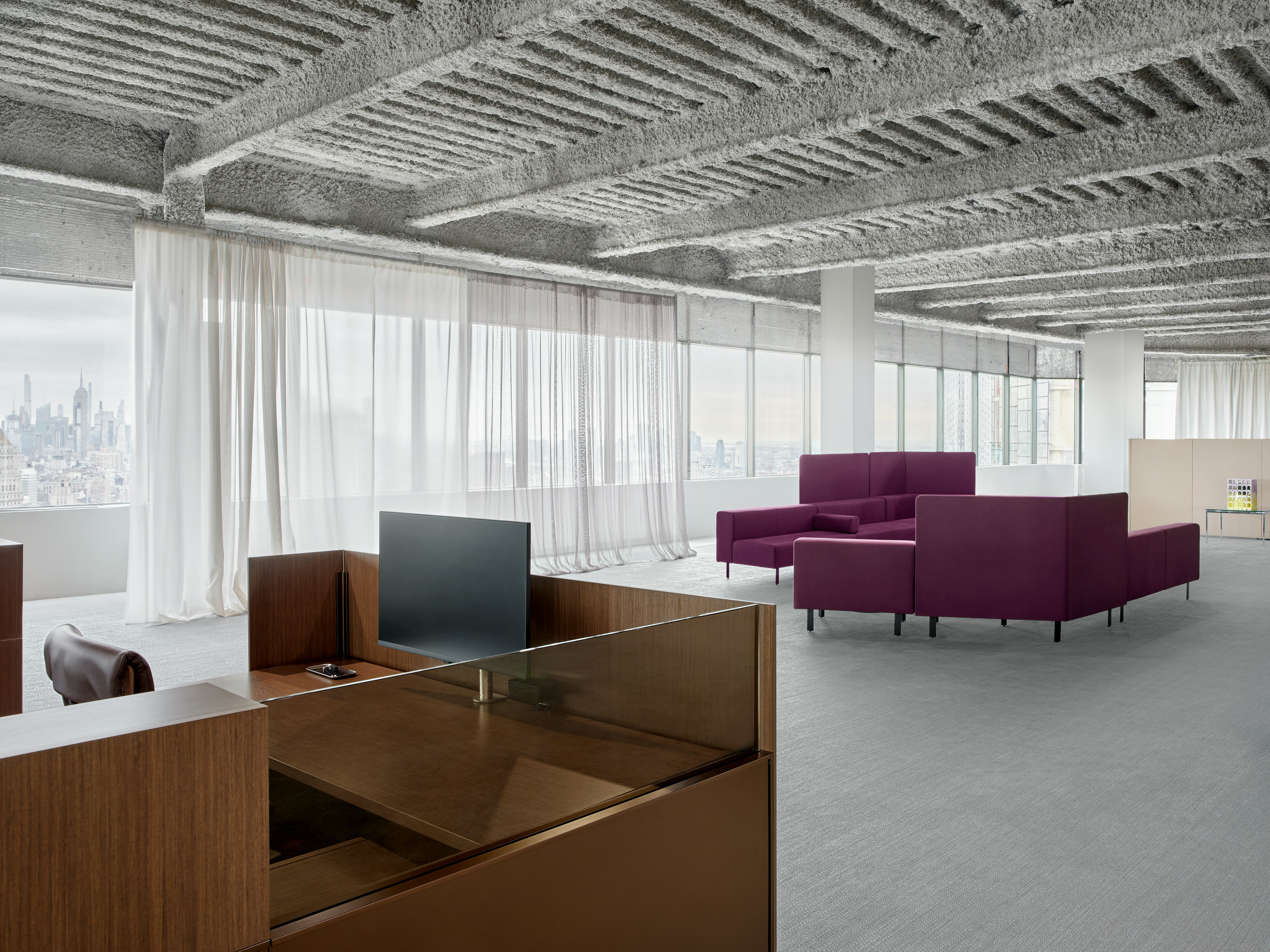 This environmental image of a Dividends Skyline workstation with lounge seating in the background is in an open office space.