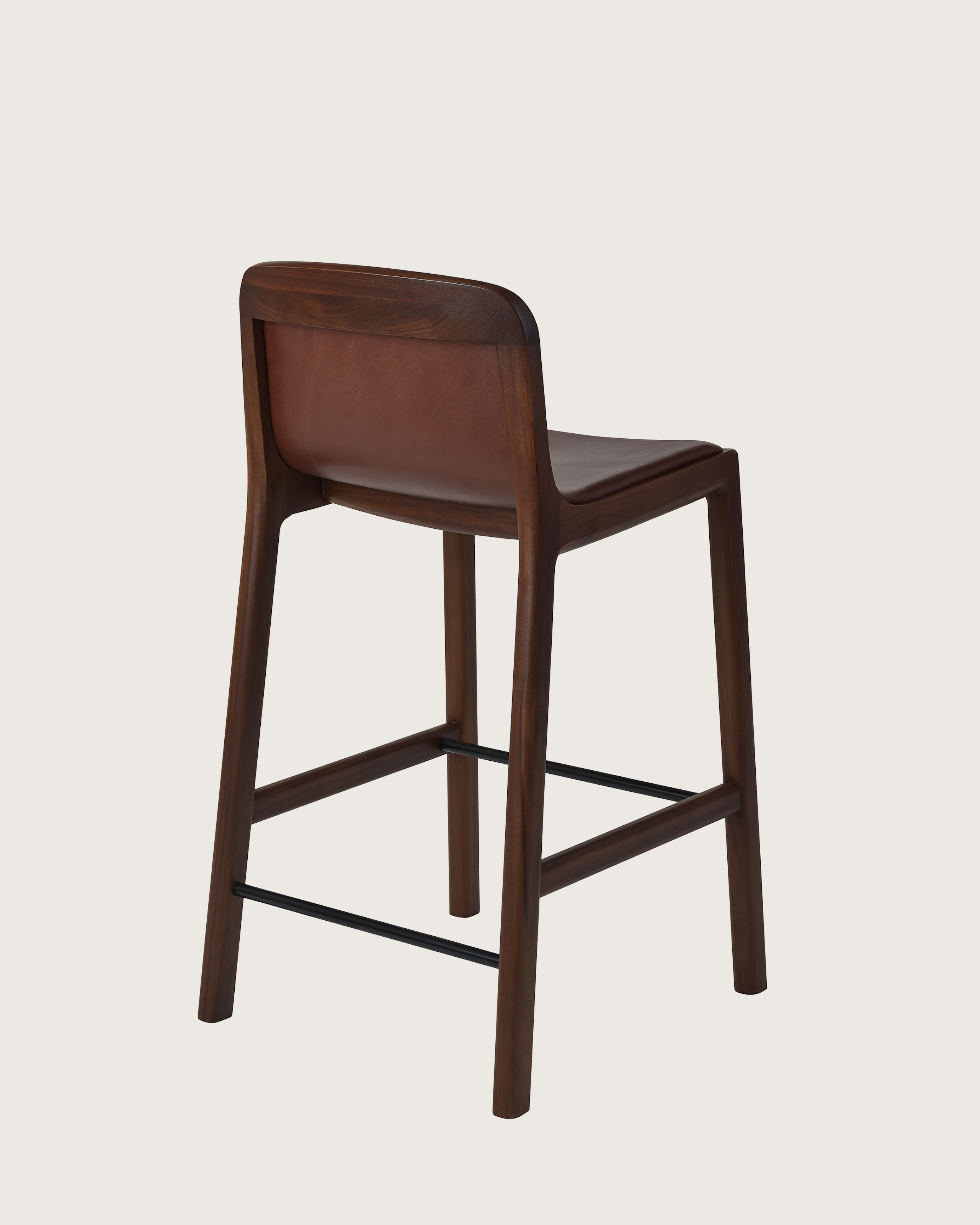 Lijn Stool by Carole Baijings for Geiger in Persian Walnut frame upholstered with Maharam Hue Leather in Bittersweet, angled back view on a white sweep.