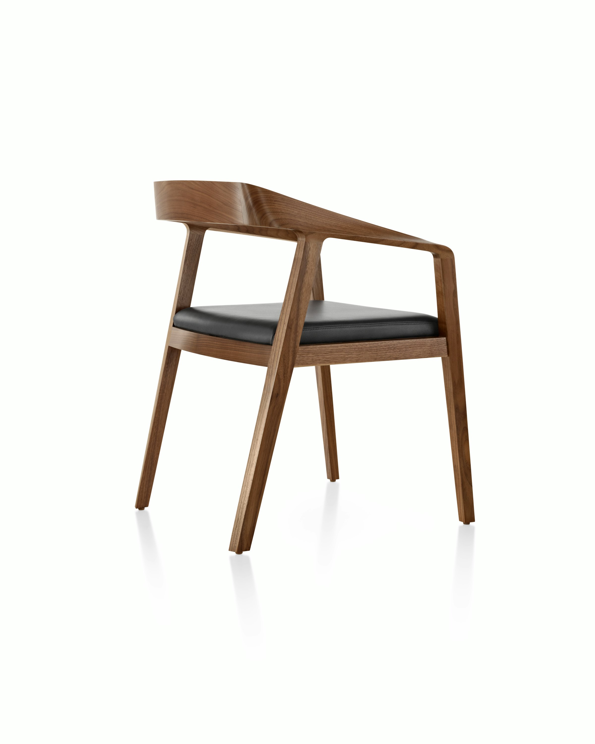 A Full Twist Guest Chair with a black leather seat pad and a wood frame in a medium finish, viewed from behind at an angle.