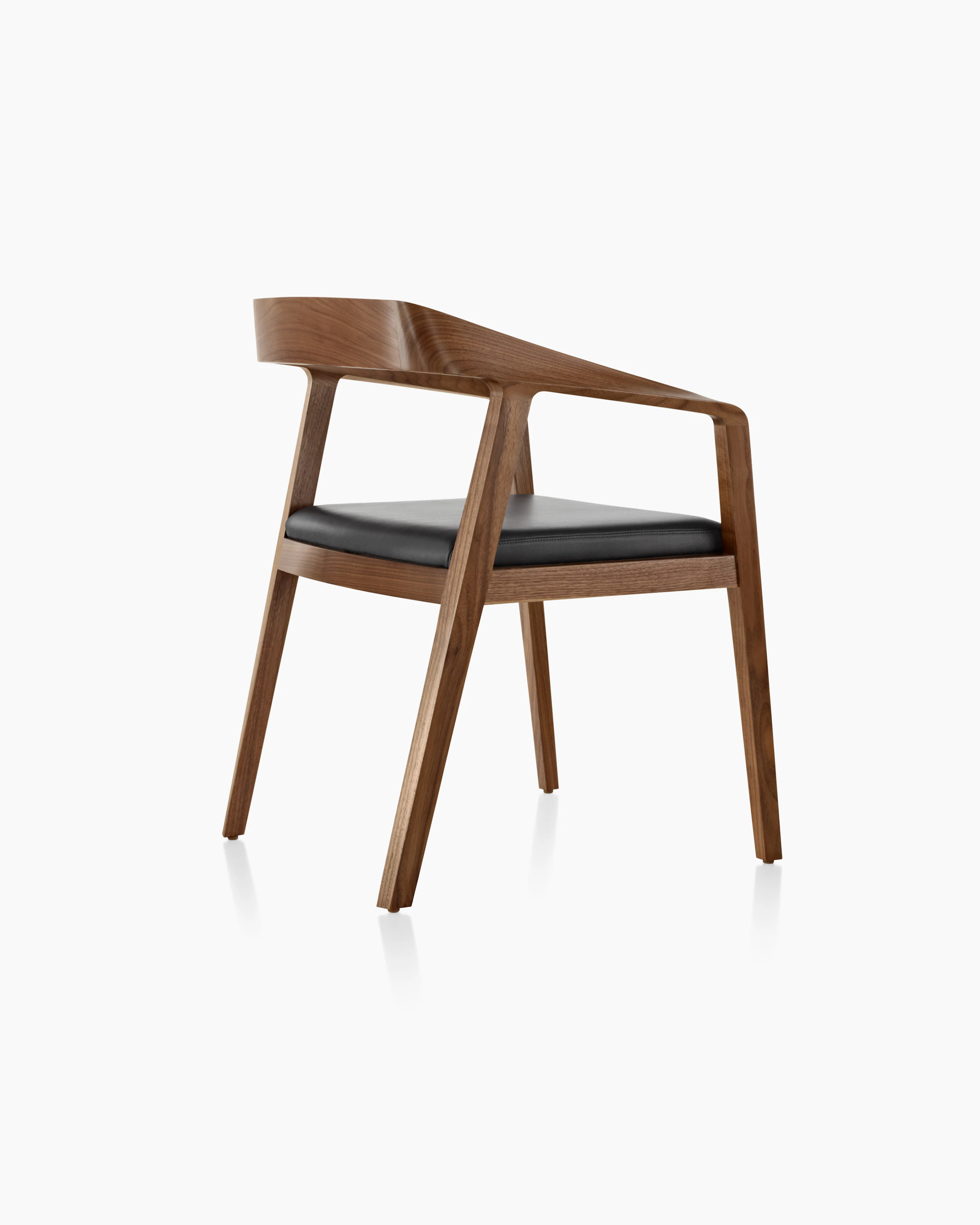 A Full Twist Guest Chair with a black leather seat pad and a wood frame in a medium finish, viewed from behind at an angle.