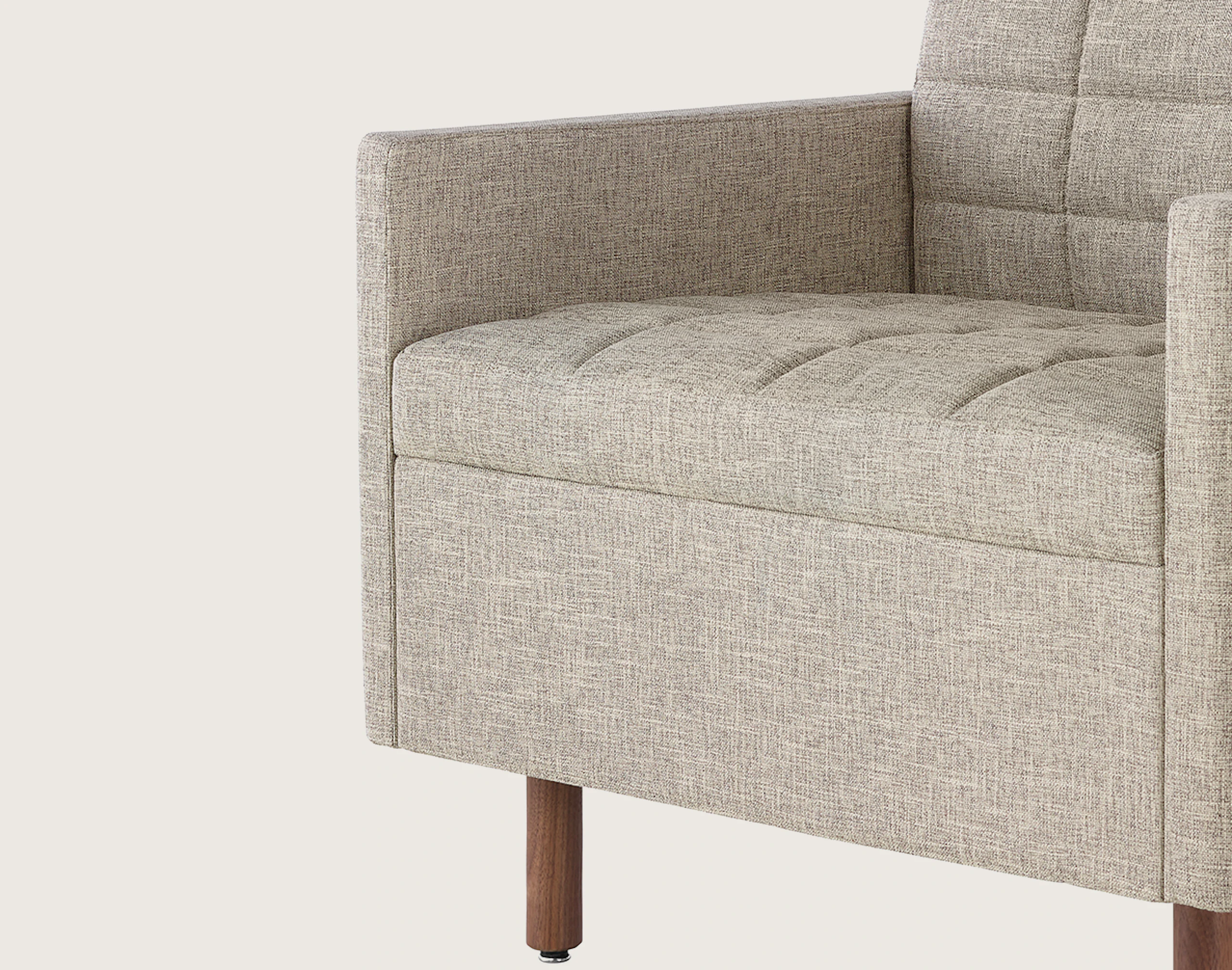 Angled view of a quilted Tuxedo Classic club chair upholstered in bone-colored fabric
