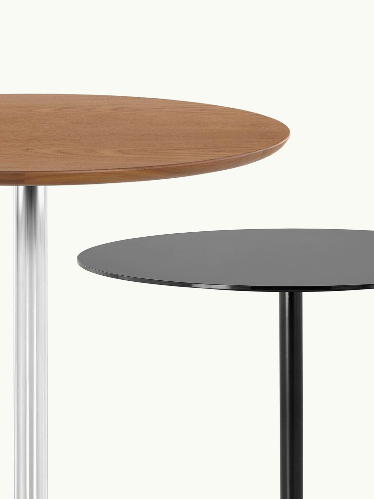 Close-up of two Saiba Tables staggered, one with a Walnut tabletop and a chrome base, one in all black, with only partial tabletops and columns visible, on a white sweep.