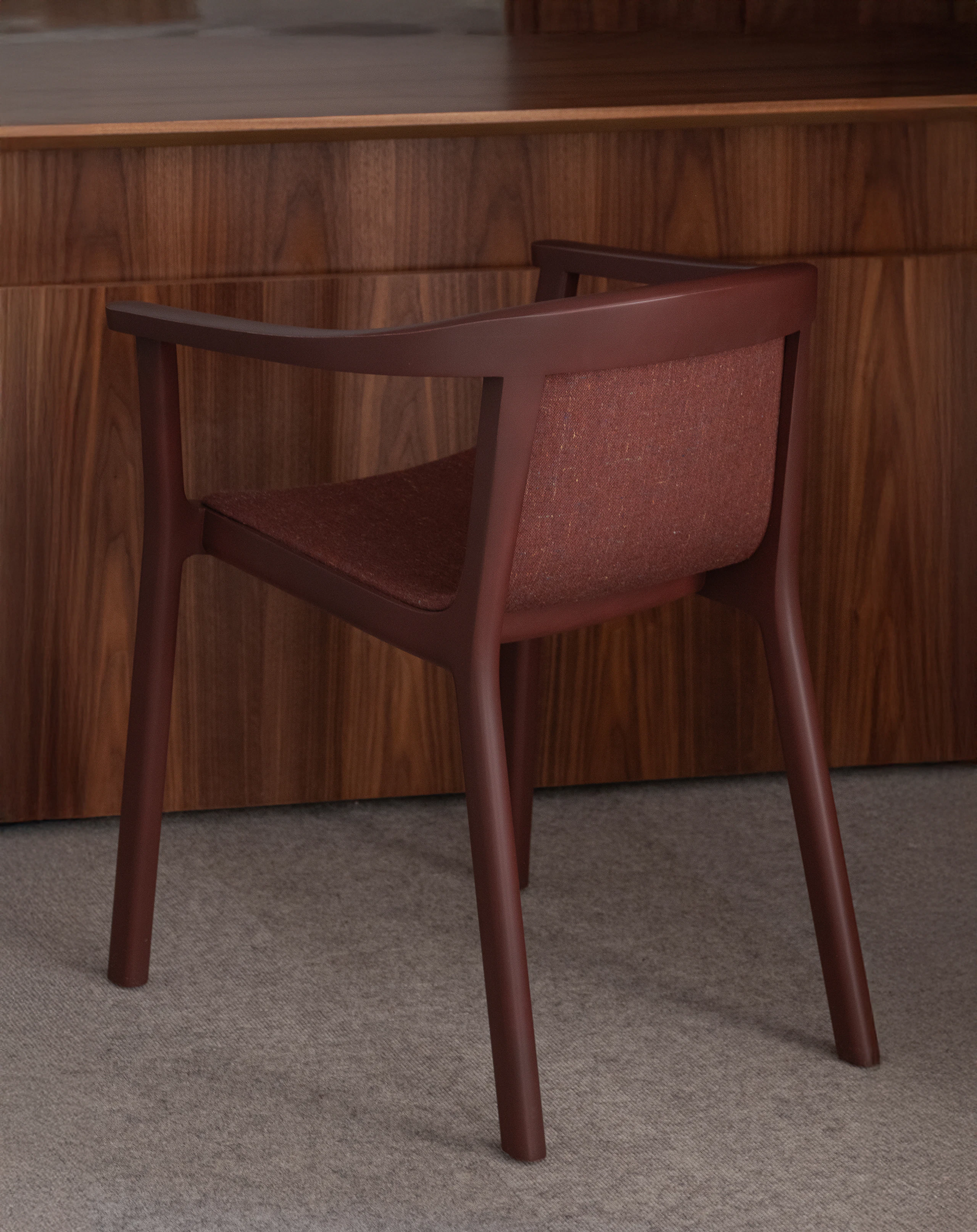 Lijn Armchair designed by Carole Baijings in Red Clay, fully upholstered with Rowan in Bordeaux, viewed from behind at an angle in a private office setting.