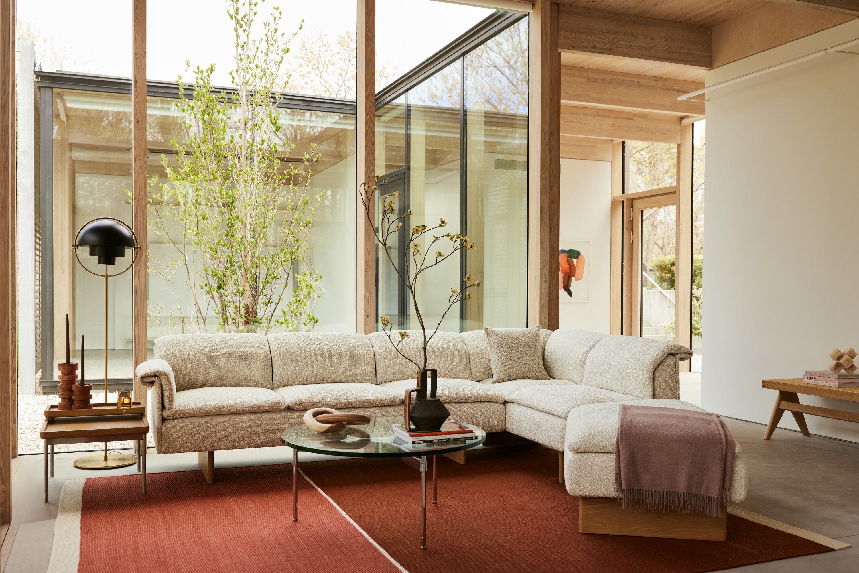 A Geiger residential setting with a Mantle Sectional, Claw Coffee Table and Tuxedo Tray Table, featuring a DWR lamp.