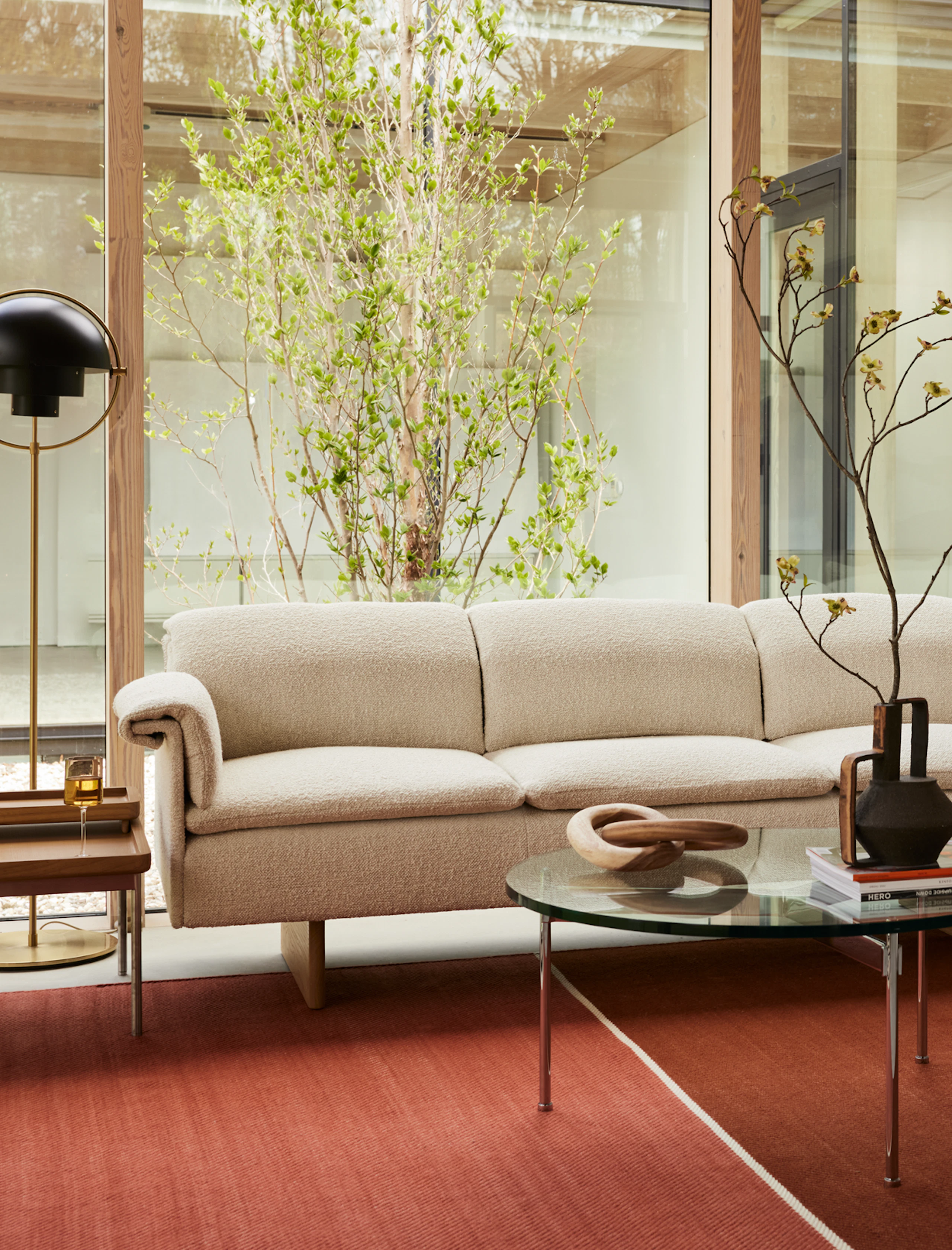 A Geiger residential setting with a Mantle Sectional, Claw Coffee Table and Tuxedo Tray Table, featuring a DWR lamp.