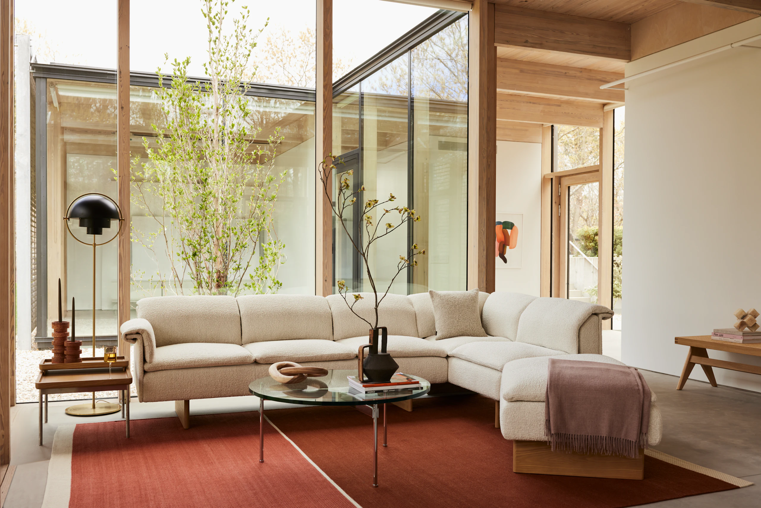 A Geiger residential setting with a Mantle Sectional, Claw Coffee Table and Tuxedo Tray Table, featuring a DWR lamp.