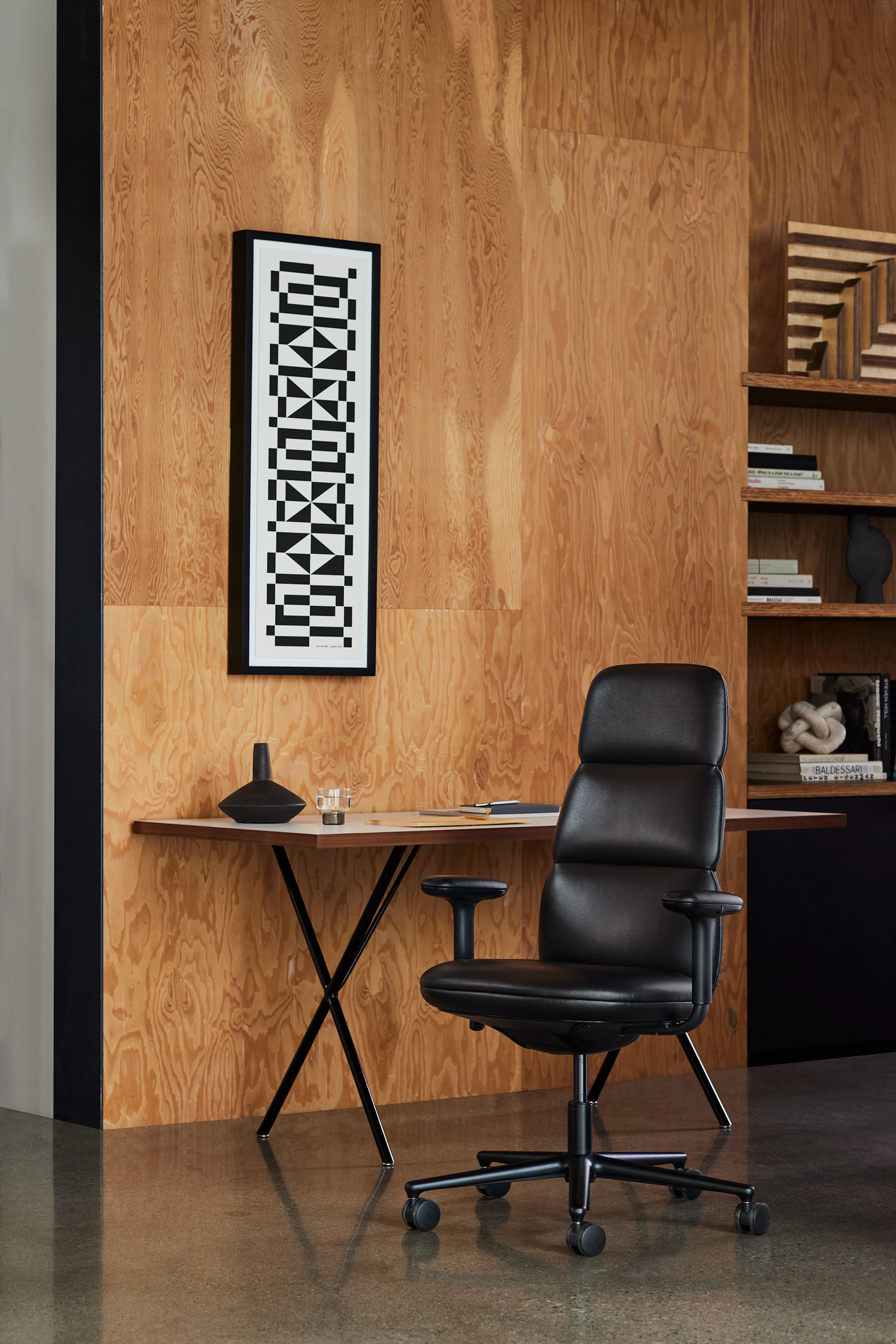 High-back Asari chair by Herman Miller in black leather in a wooden paneled library room with Nelson X-leg table.
