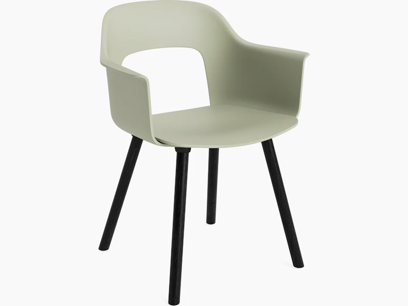 Layout Armchair 221 with pastel green plastic shell and black wood base, angled view on white background.