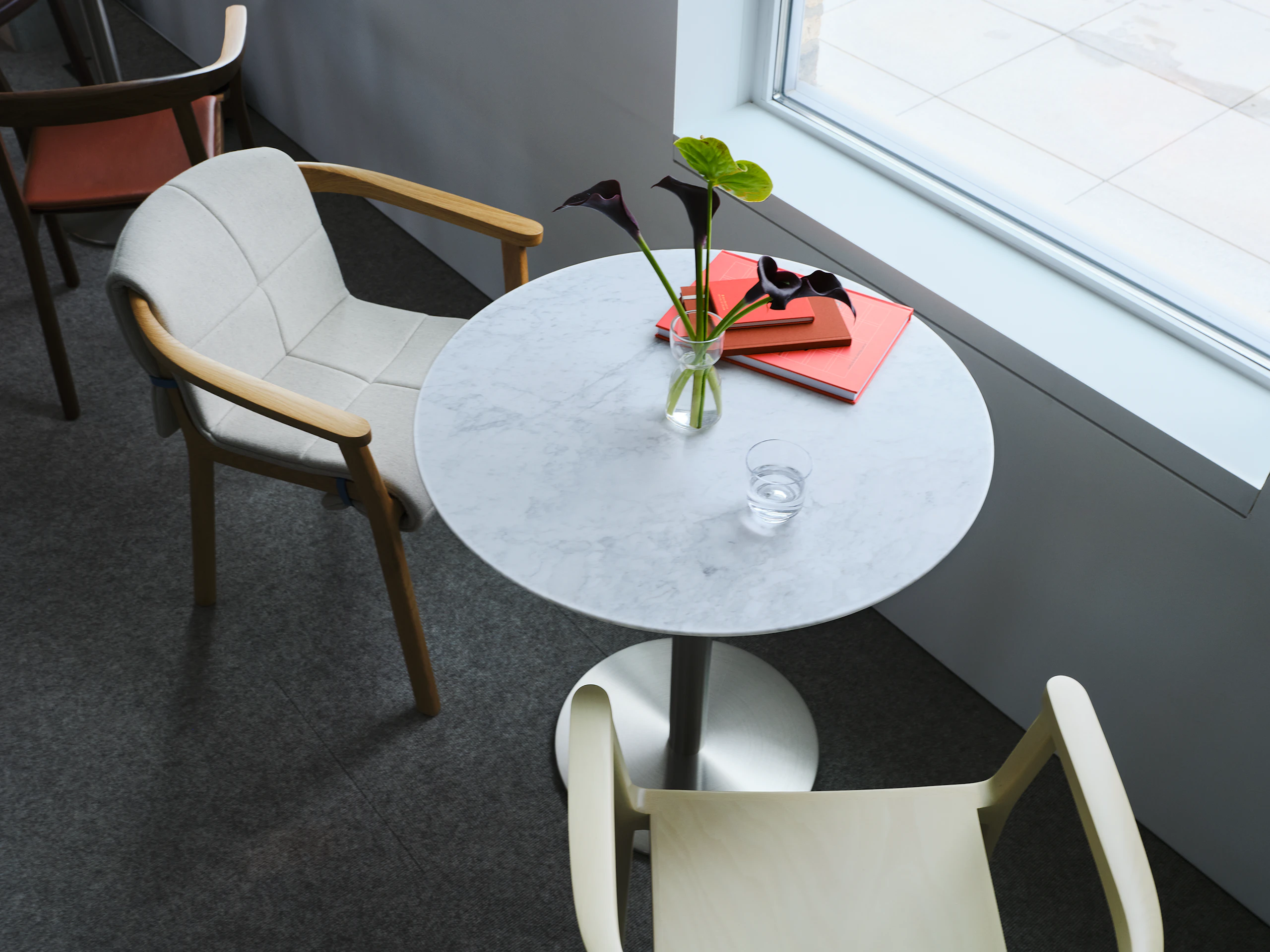 Lijn Armchairs by Carole Baijings for Geiger, shown in veneer and quilted wrap variations with NL1 Table, viewed from above with notebooks and a vase of flowers on the table in the Geiger Chicago Showroom.