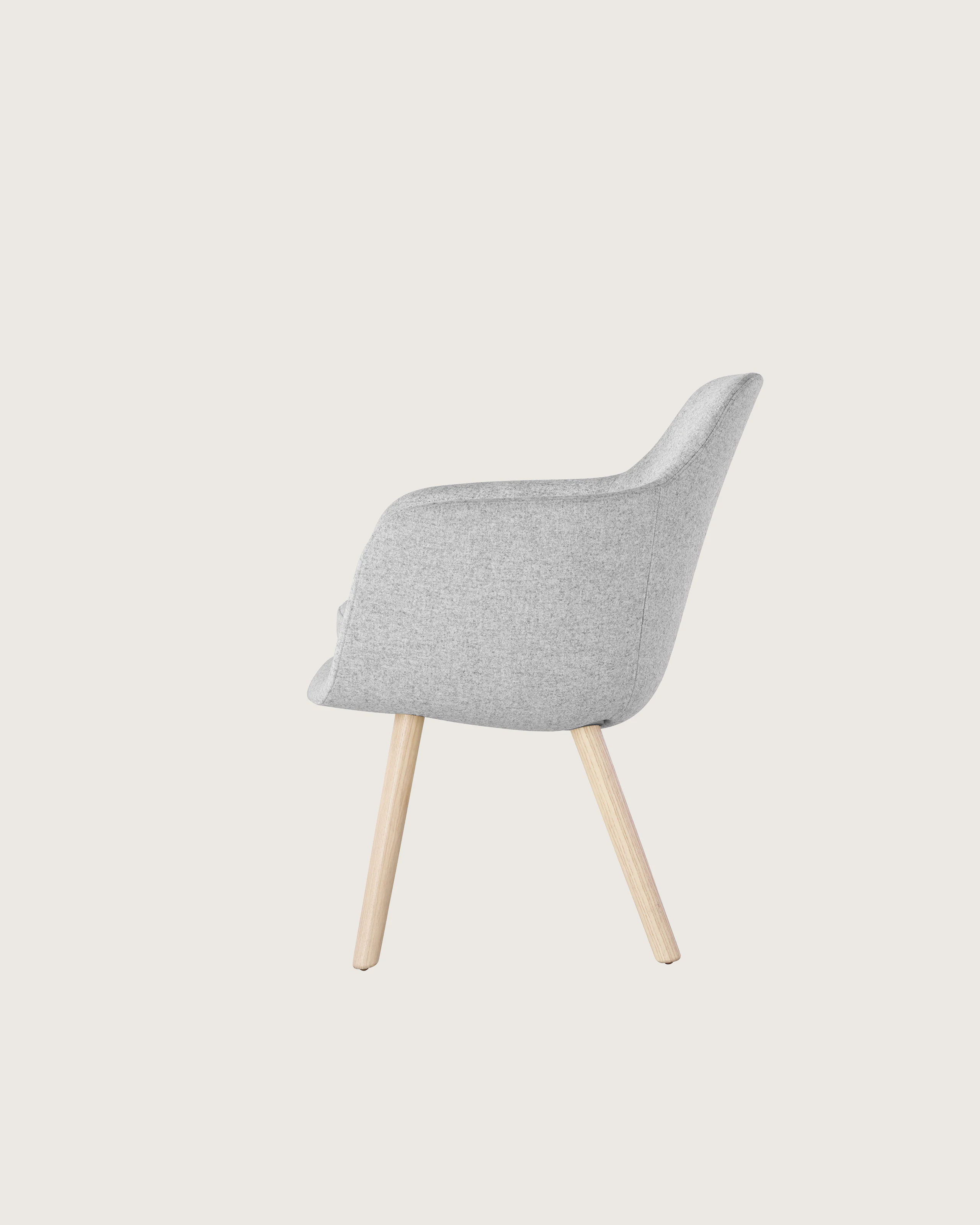 Side view of a Saiba Side Chair with light gray upholstery and wood legs in a light finish.