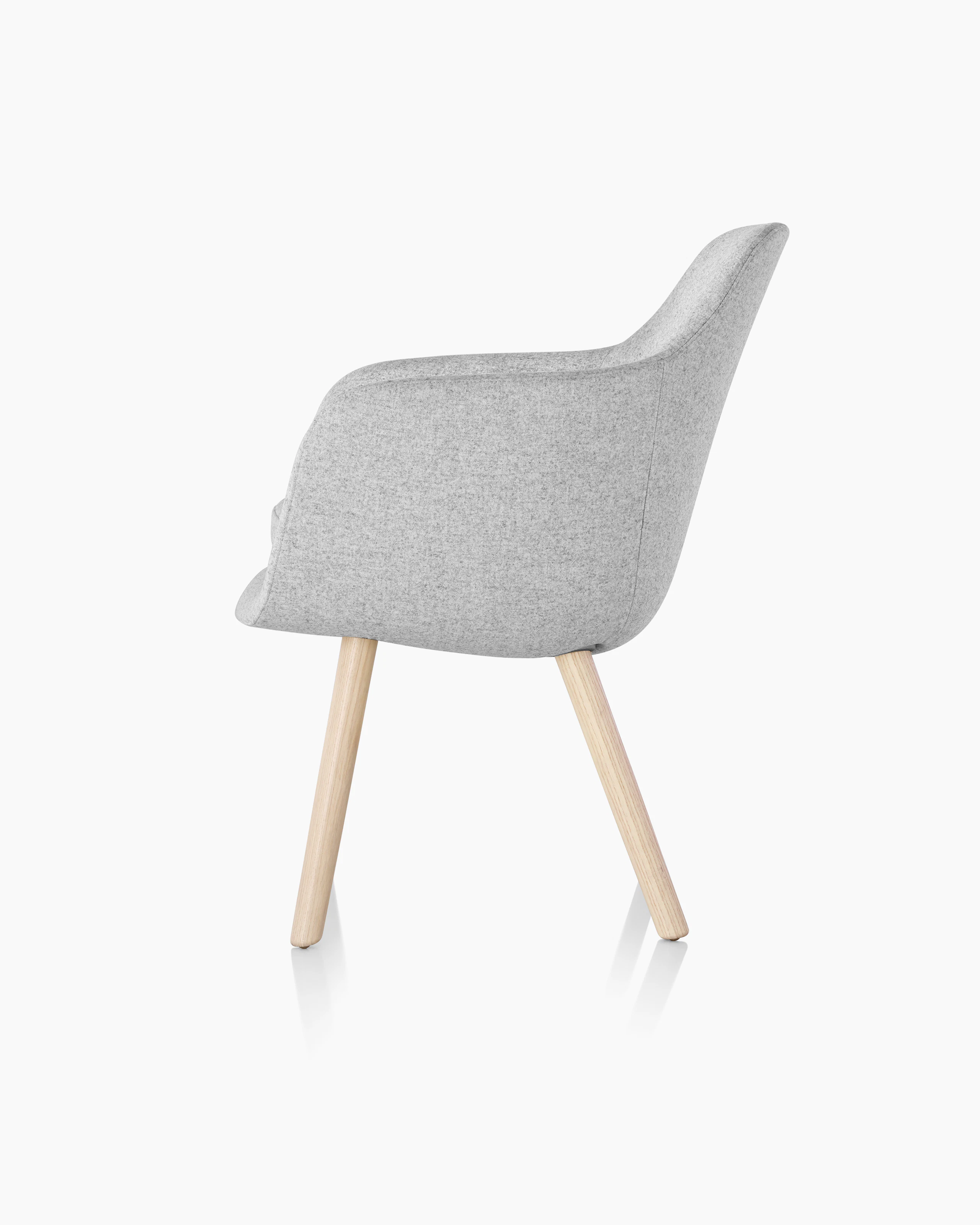 Side view of a Saiba Side Chair with light gray upholstery and wood legs in a light finish.