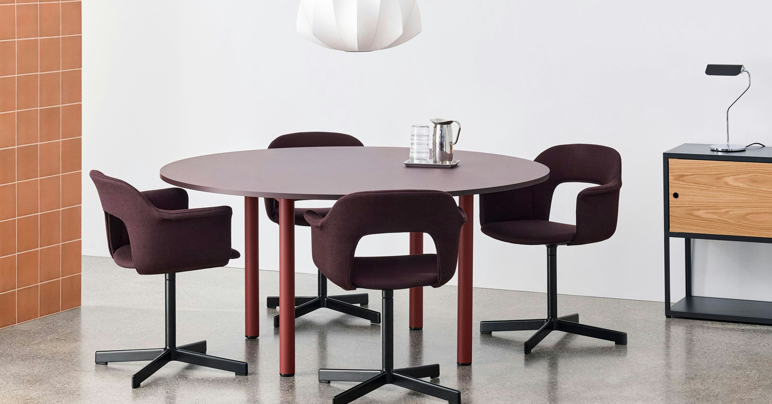 Annex round table, staged with layout chairs and white pendant light in a dining setting.