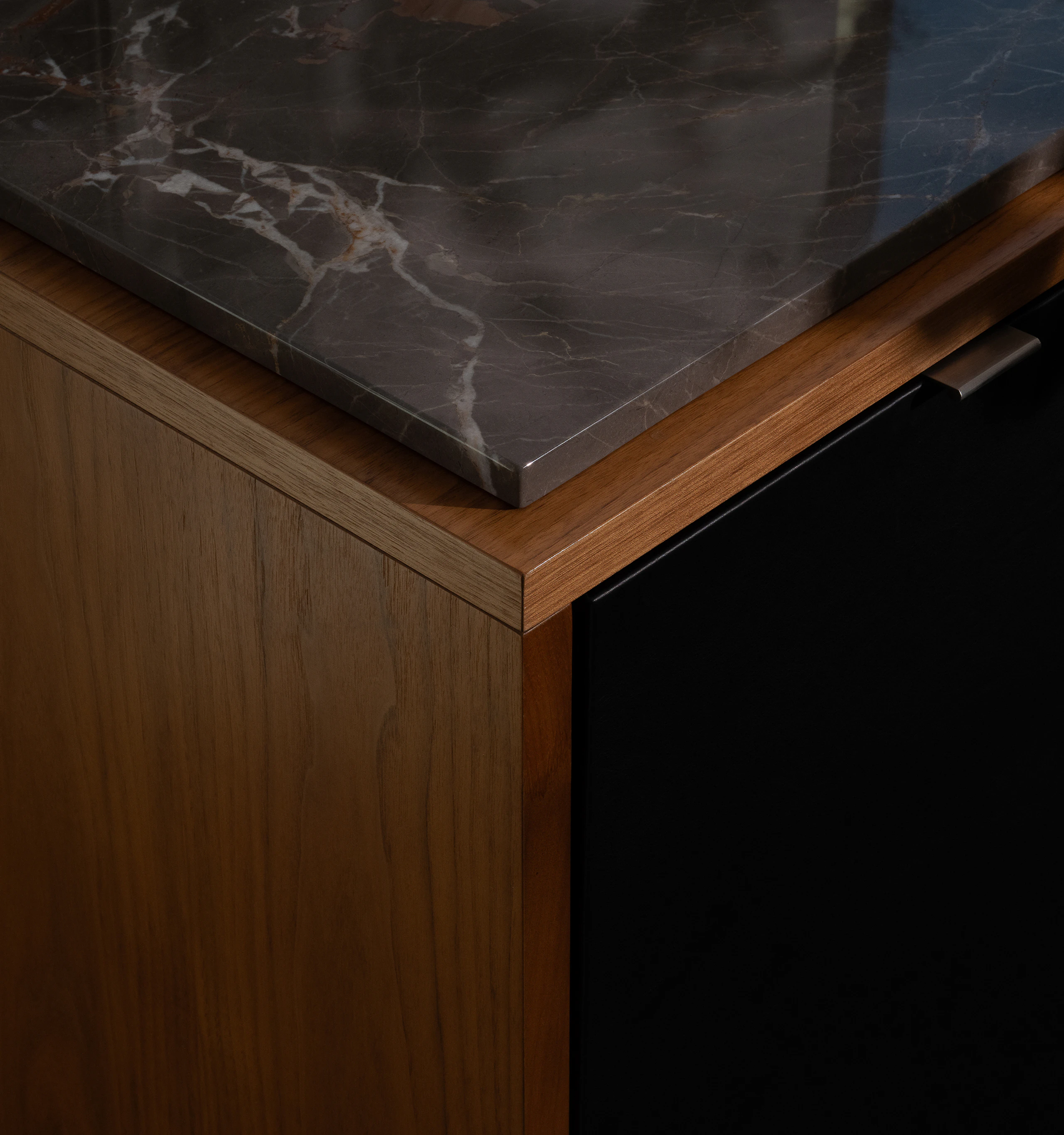 Detail view of a Highline Fifty Credenza corner in Plain Sliced Walnut with an Ombre di Caravaggio Marble Top and black leather fronts, viewed from above at an angle.