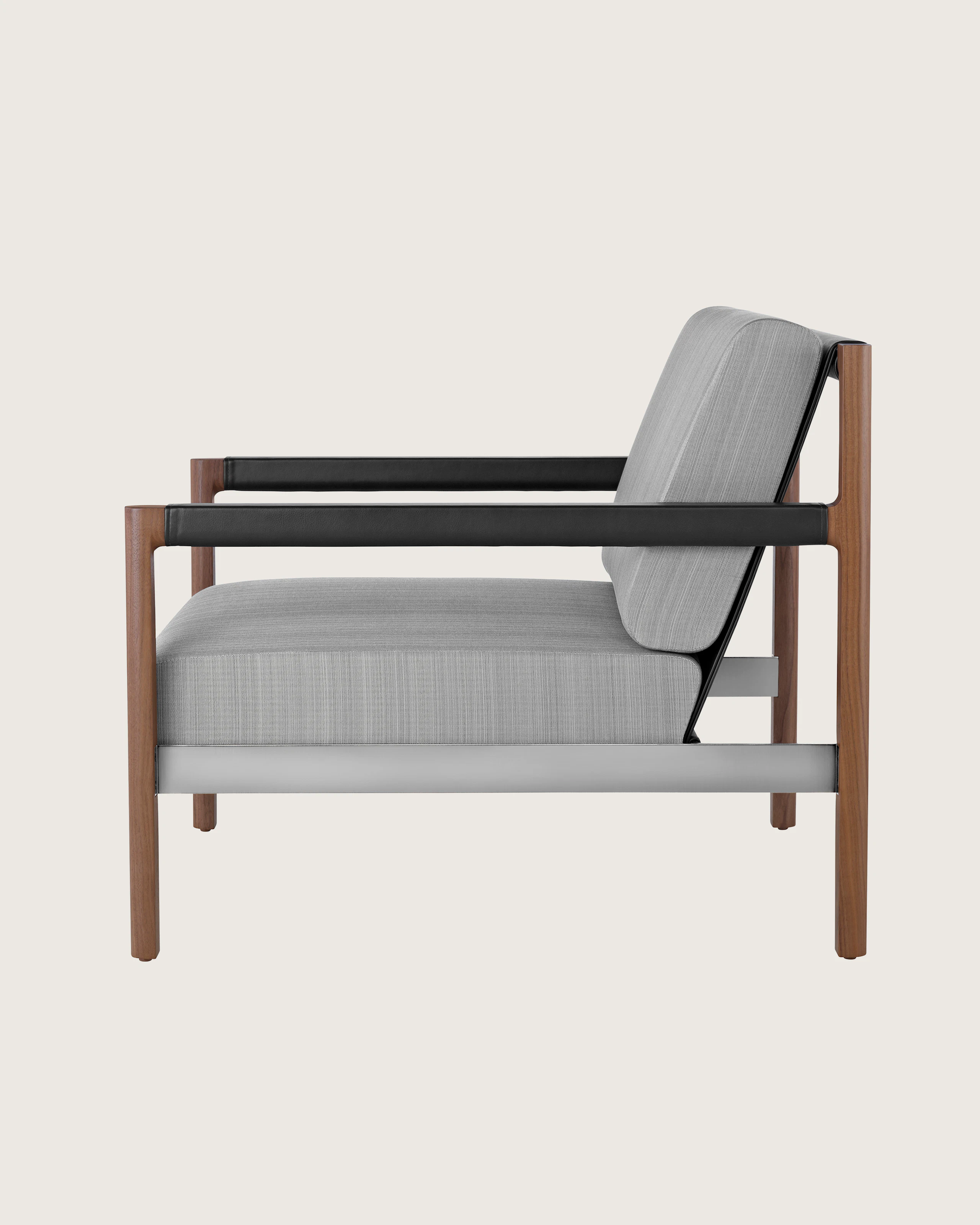 A Brabo Club Chair with light gray upholstery, leather and metal accents, and an exposed wood frame. Viewed from the side.
