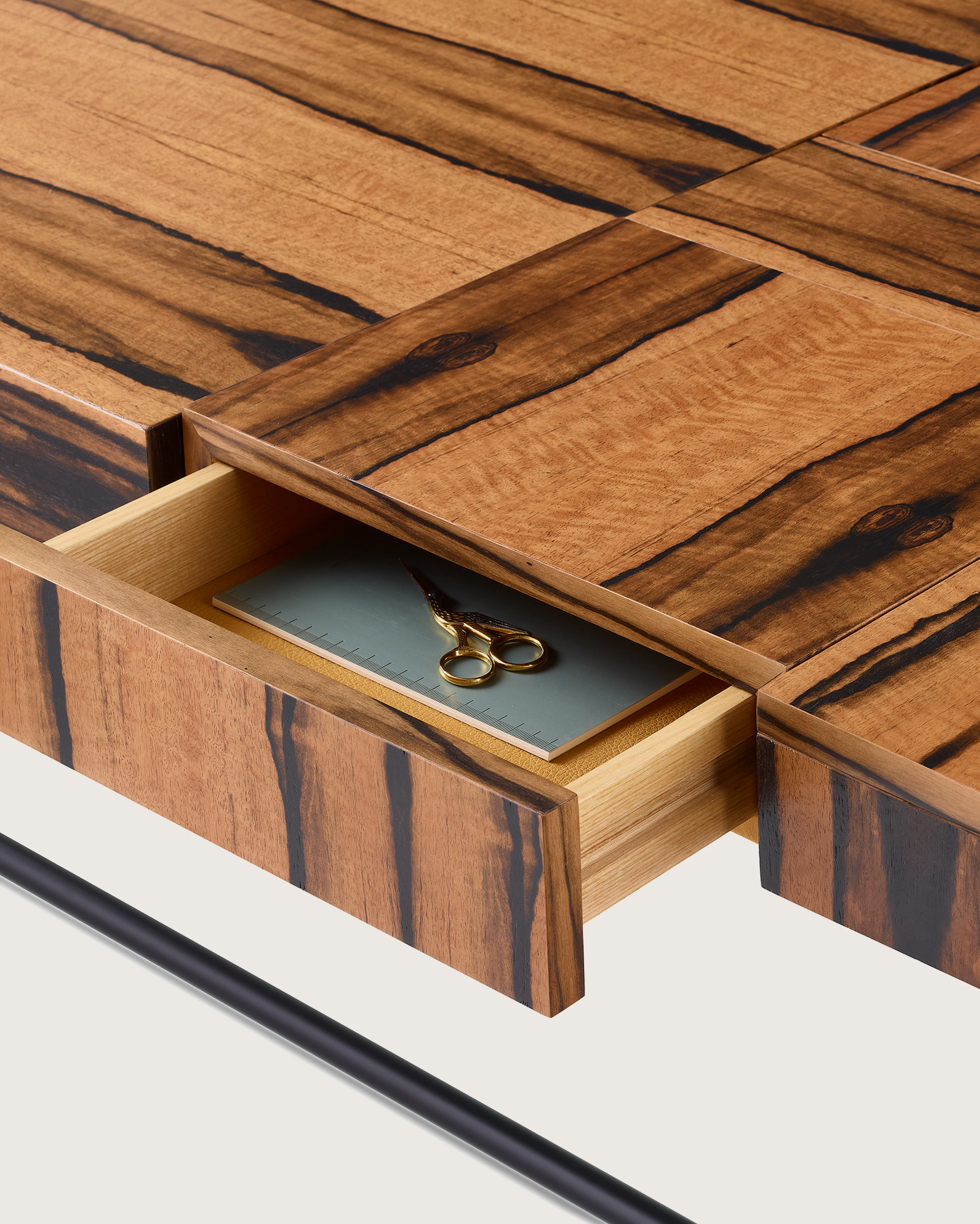 A close up of an open drawer and storage compartment of a Domino Desk with wood top and metal base.