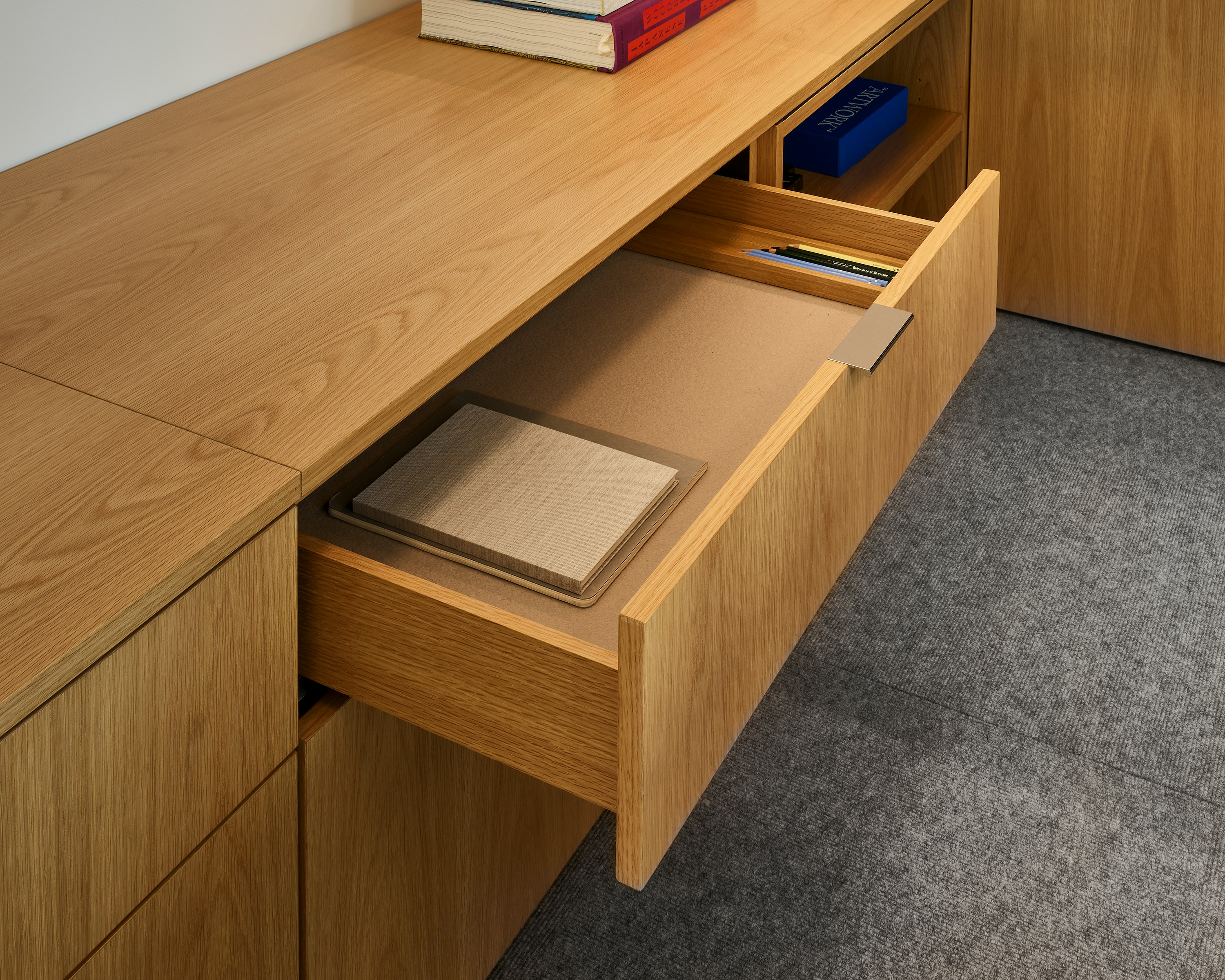 Detail view of a Geiger One Casegoods Private Office open storage drawer in Natural Flat Cut Oak, viewed at an angle in a private office setting.