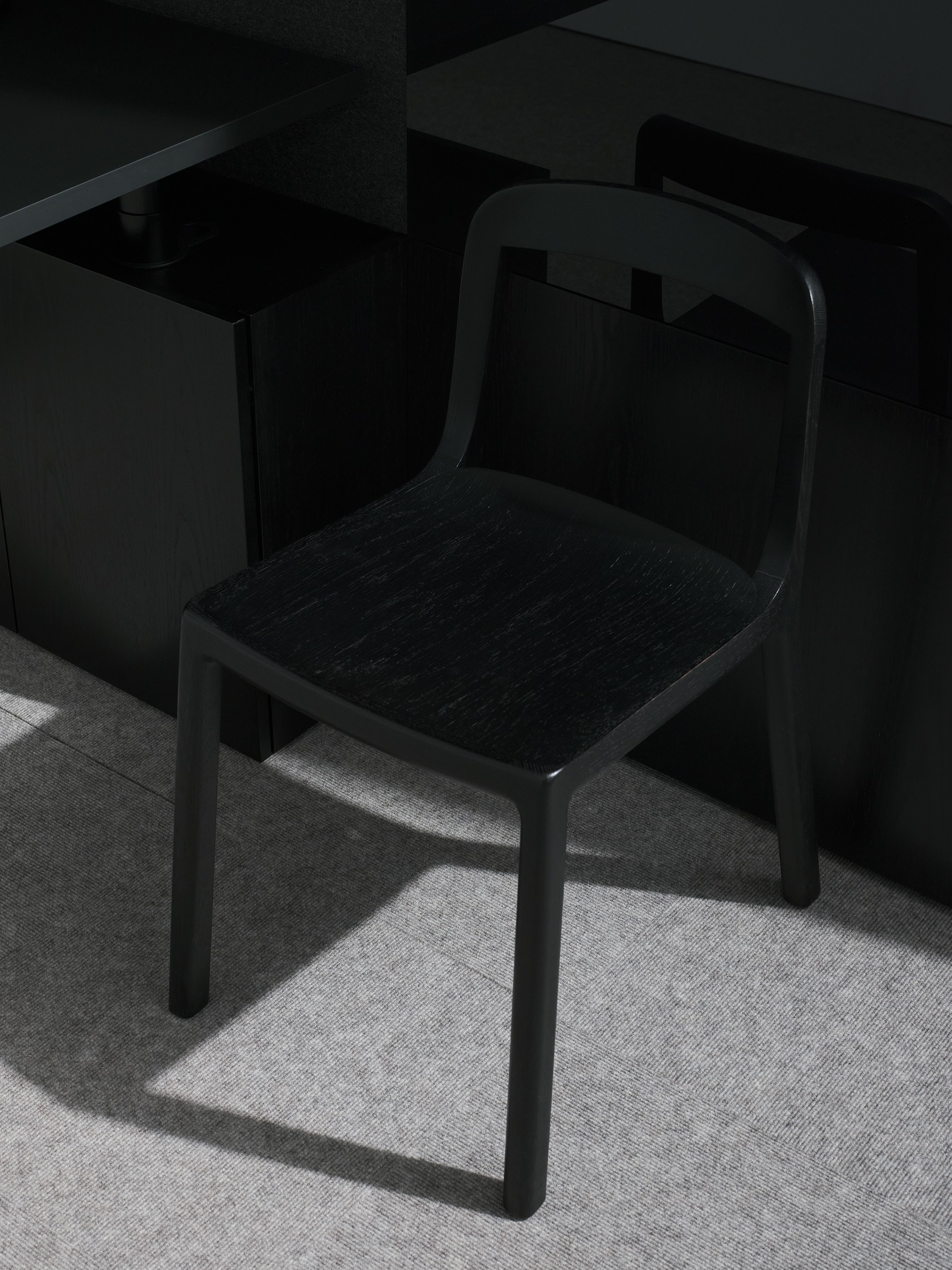 Lijn Side Chair in Ebonized Oak with an open back and wood seat in a private office setting, viewed from above at an angle.