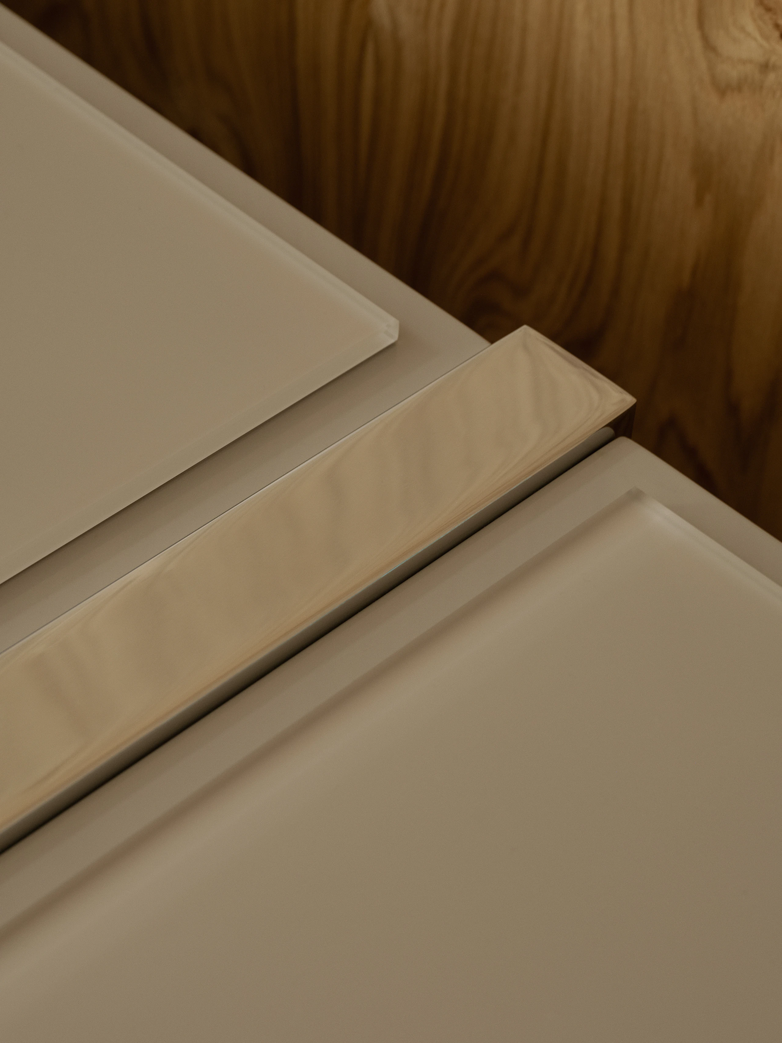 Detail view of a Highline Credenza in Taupe Satin Lacquer with an etched back painted glass top in matte Taupe with a chrome metal detail viewed from above at an angle.