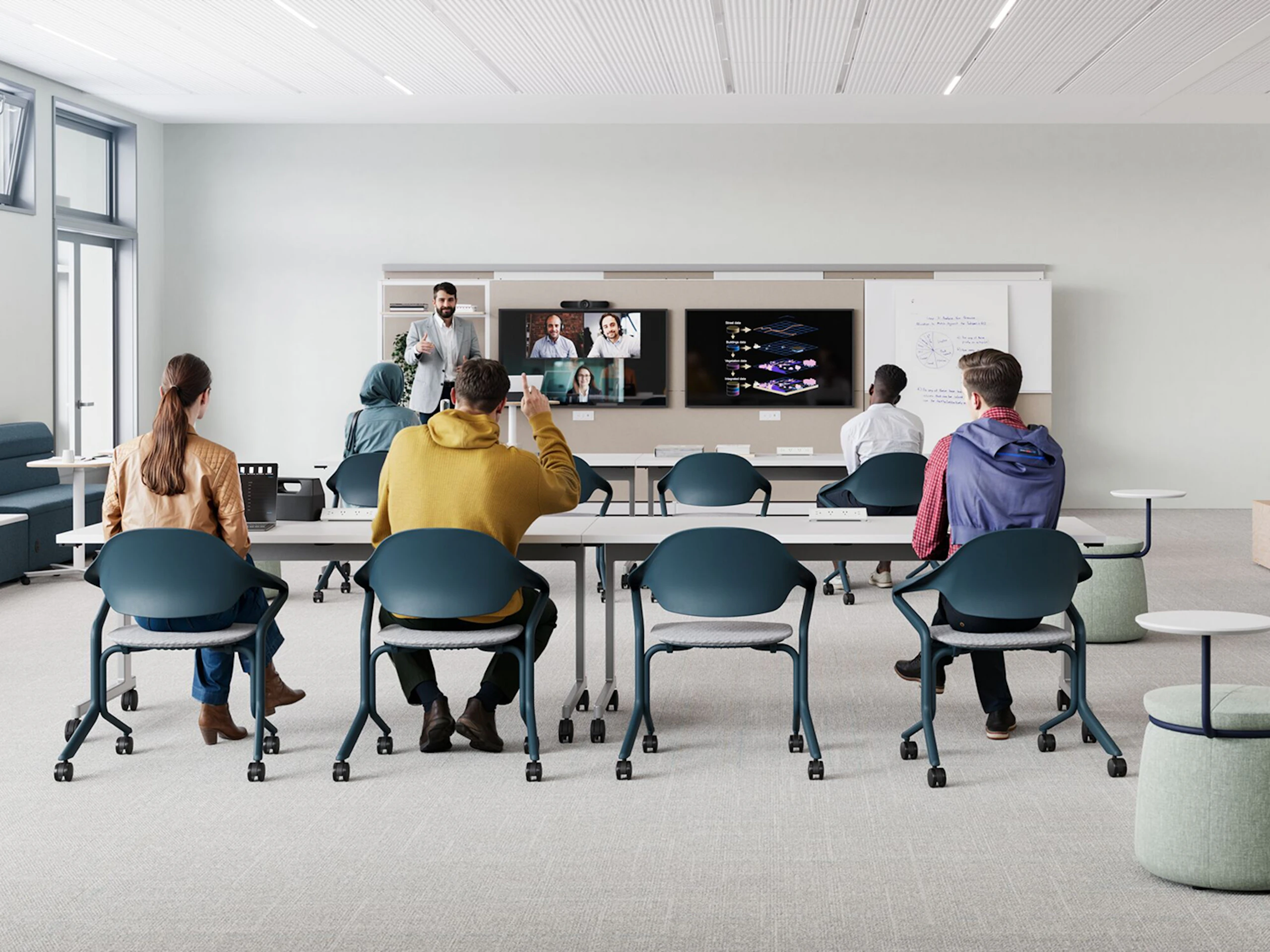 Modern classroom setting with students sitting at long white tables in blue Fuld Nesting chairs by Herman Miller.