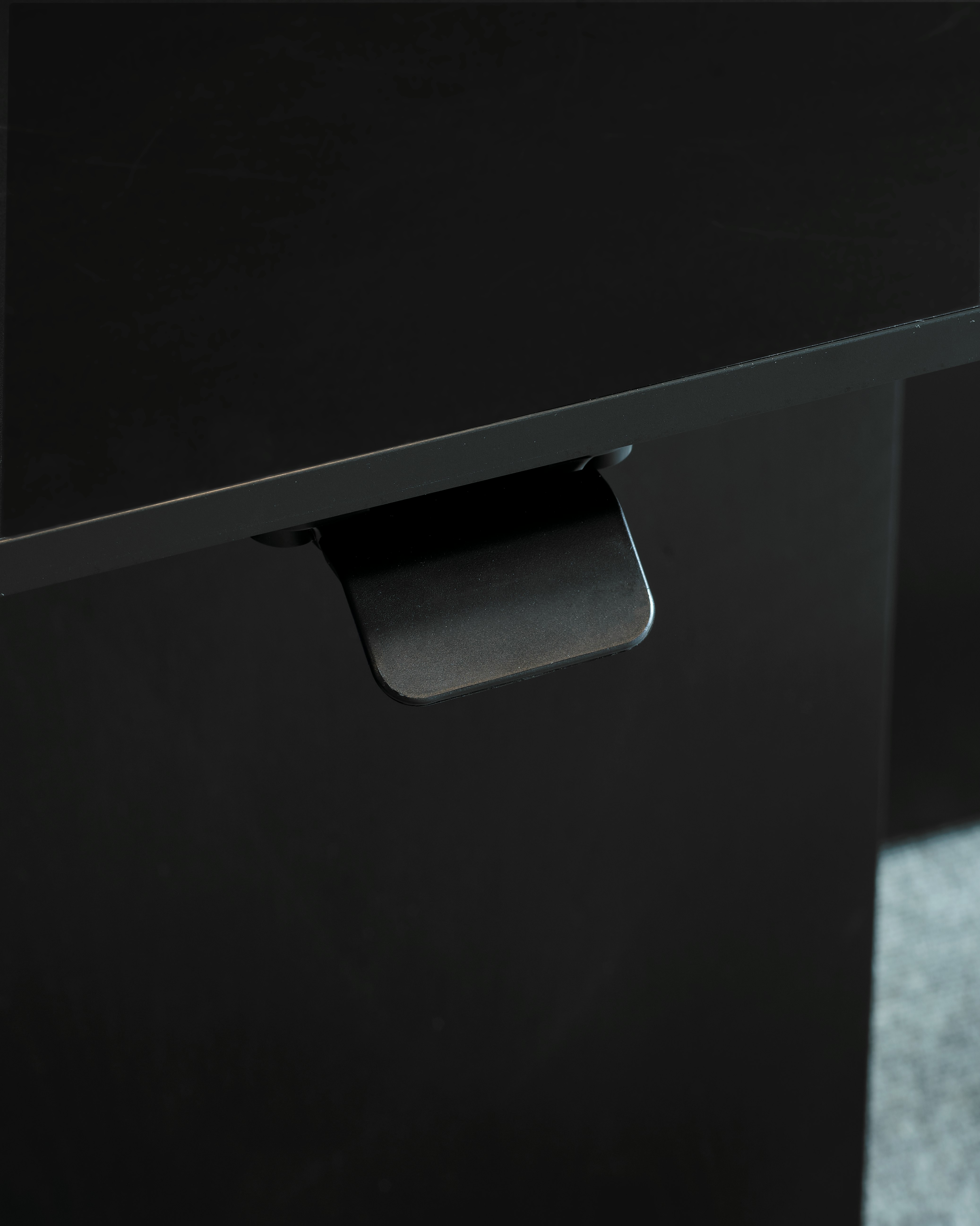 Detail view of the height-adjustable desk control for a Geiger One Private Office work surface in black with the display screen turned off, viewed at an angle.