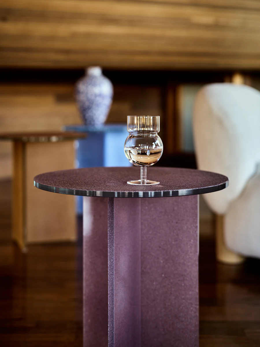 Tall gold textured table with round top and a V-shaped base shown from lower angle.