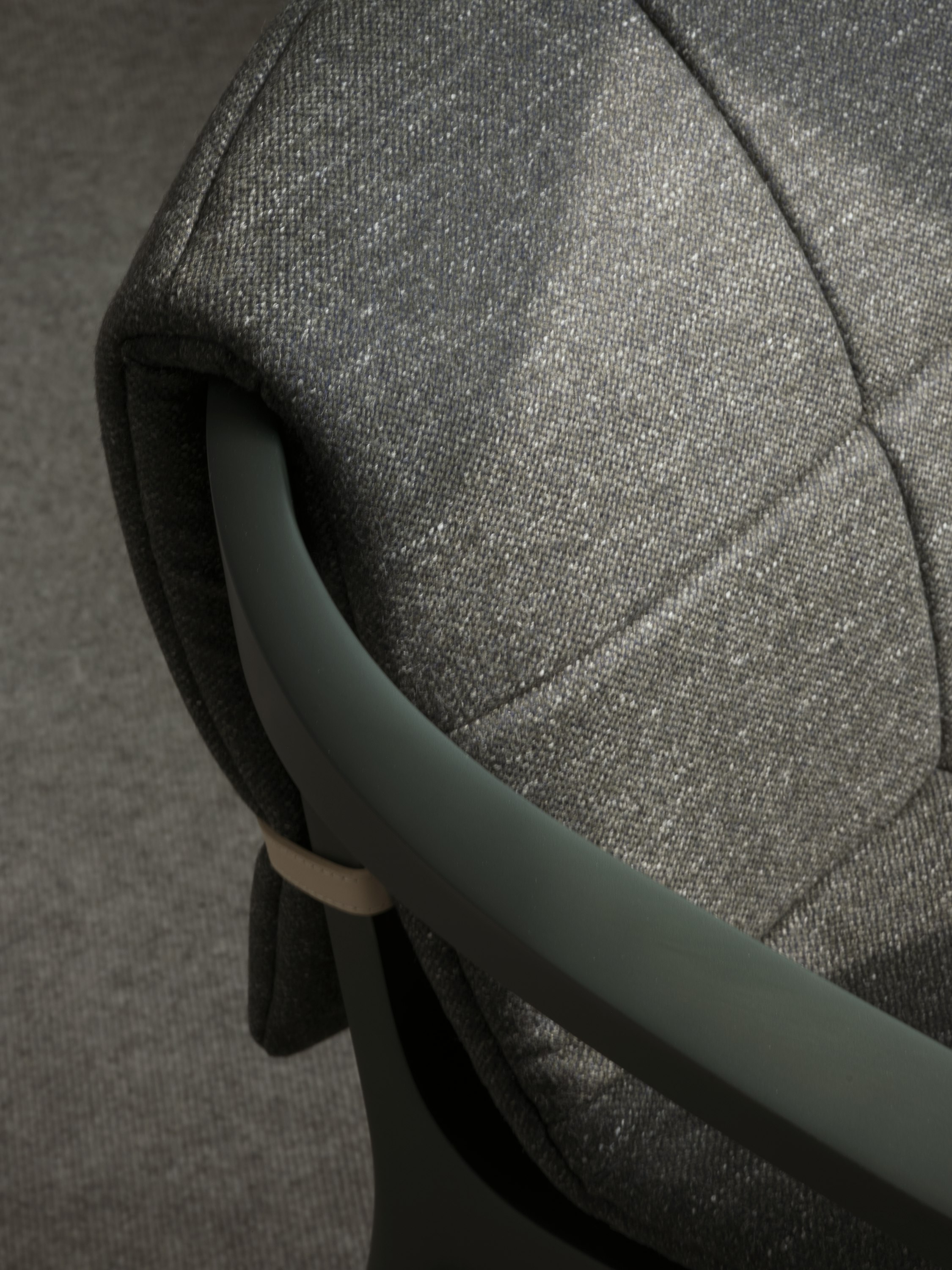 Detail view of a Lijn Armchair back and armrest in Ivy with a quilted wrap in Bellano Black Green, viewed from above at an angle.